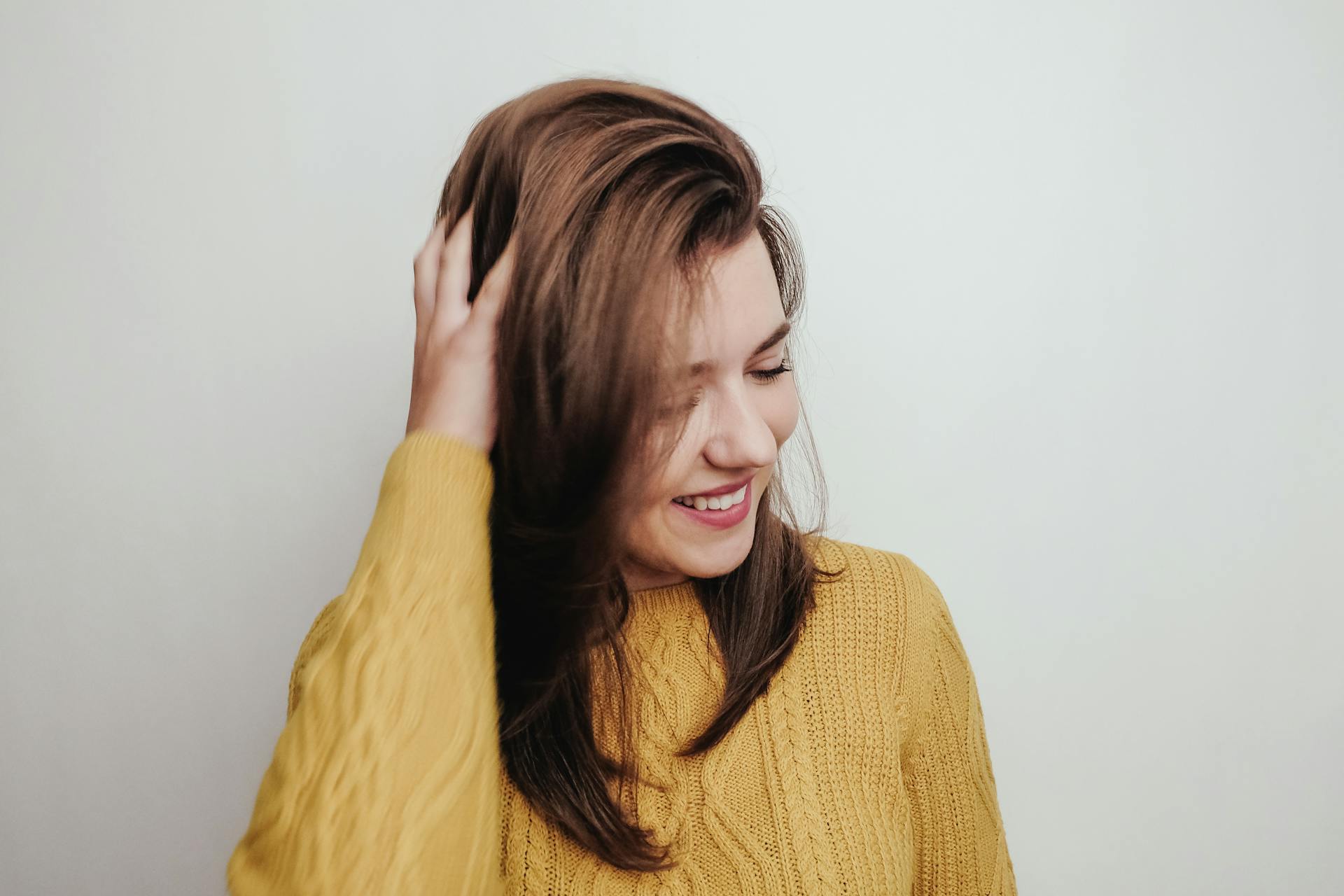 A woman ruffling her hair and smiling | Source: Pexels