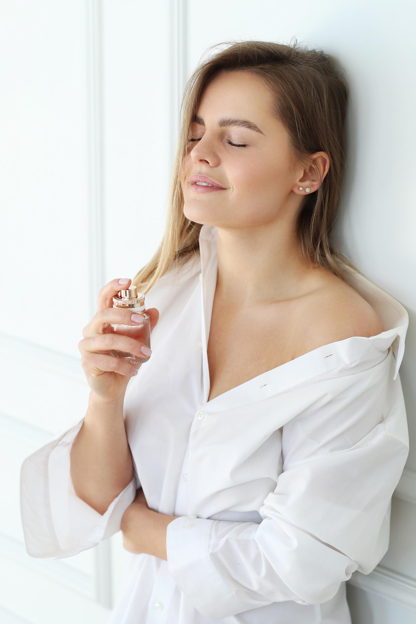 A young woman applying perfume | Source: Freepik