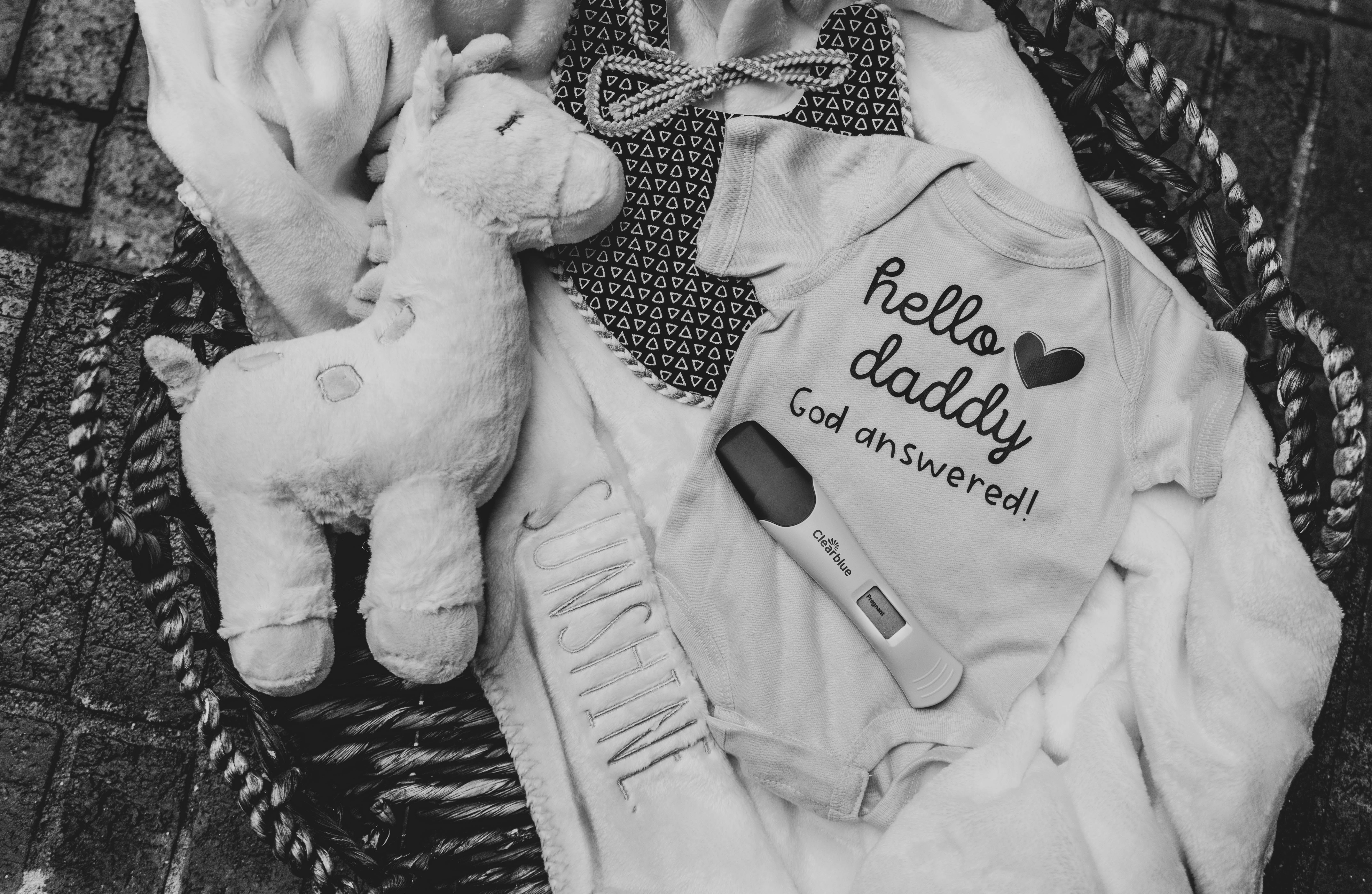 Peluche, ropa de bebé y test positivo de embarazo. | Foto: Unsplash
