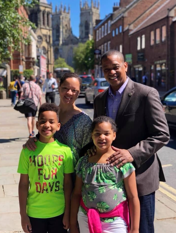 Justin and Cerina Fairfax stand with Cameron and Carys on a city street during a daytime outing | Source: Facebook/justin.fairfax.2025