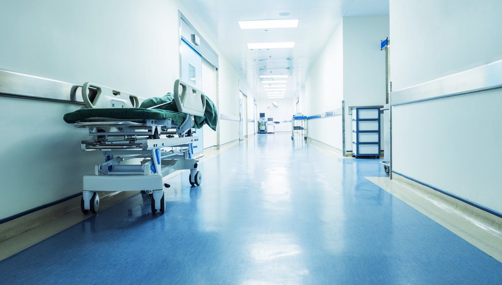 A hospital hallway with an empty gurney standing on the side | Shutterstock/hxdbzxy