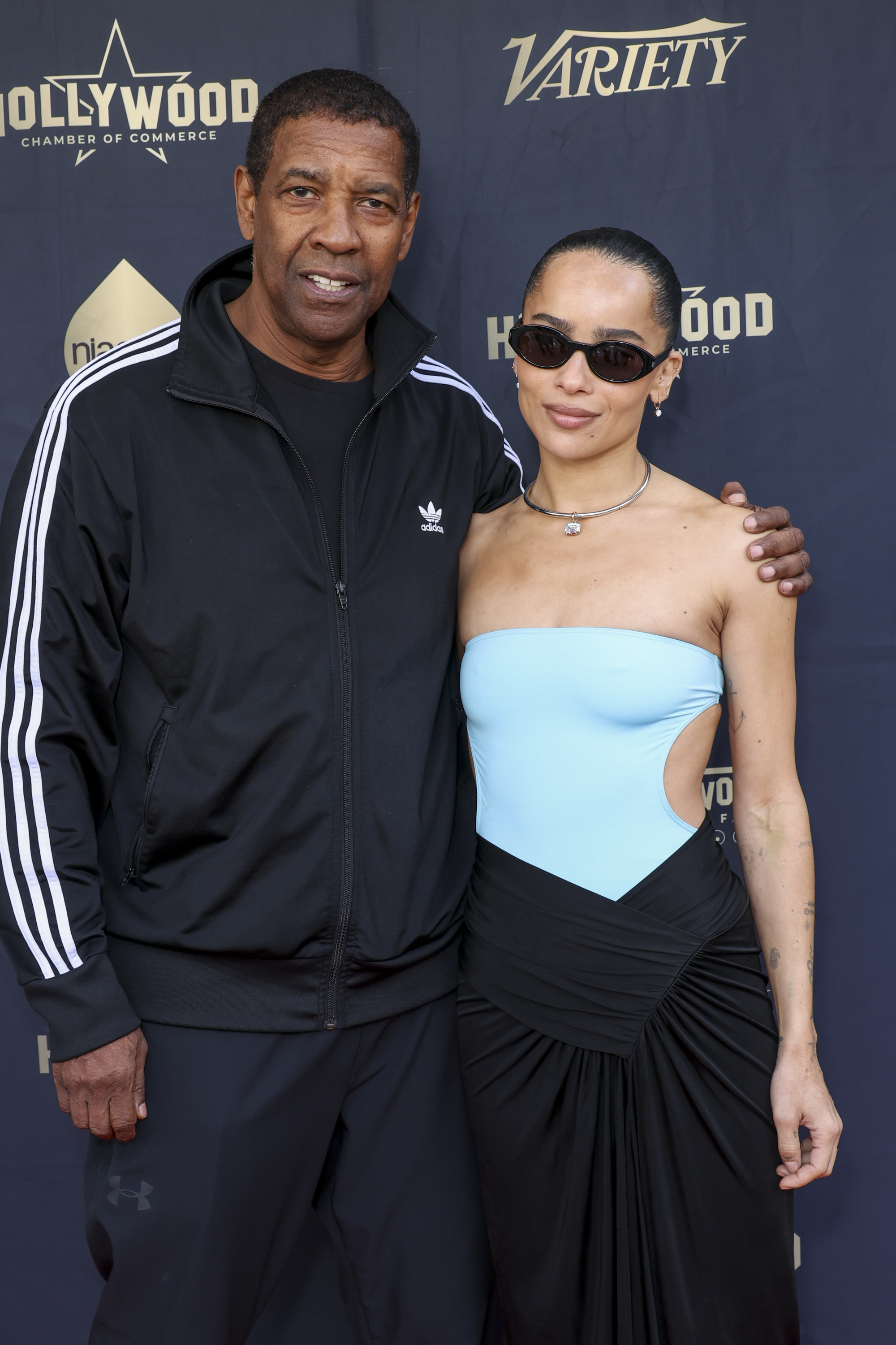 Posing with Zoë Kravitz at Lenny Kravitz’s Hollywood Walk of Fame ceremony, Denzel Washington wears a sporty Adidas tracksuit and dark t-shirt. His cropped hairstyle blends casual comfort with iconic cool.