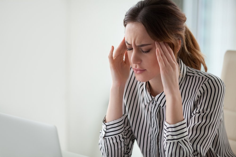 Une femme fatiguée et stressée qui se masse les temples. | Shutterstock