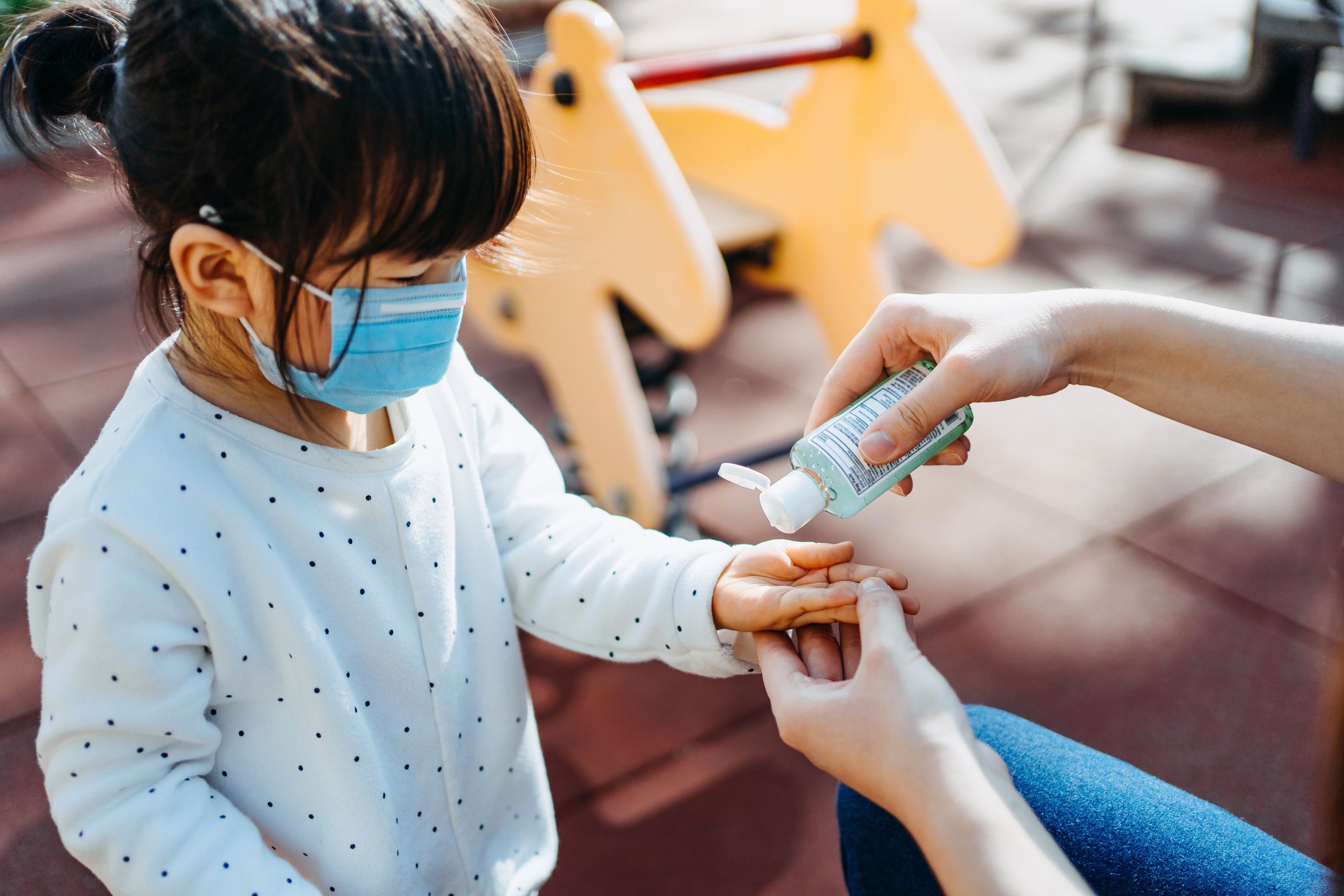 Young mother squeezing hand sanitizer onto little daughter's hand in the playground to prevent the spread of viruses | Photo: Getty Images