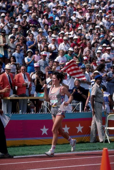 Joan Benoit of the USA carries an American flag as she takes a victory lap around the Los Angeles Memorial Coliseum following her gold medal performance in the first ever women's Olympic marathon race at the 1984 Summer Olympic Games | Source: Getty Images
