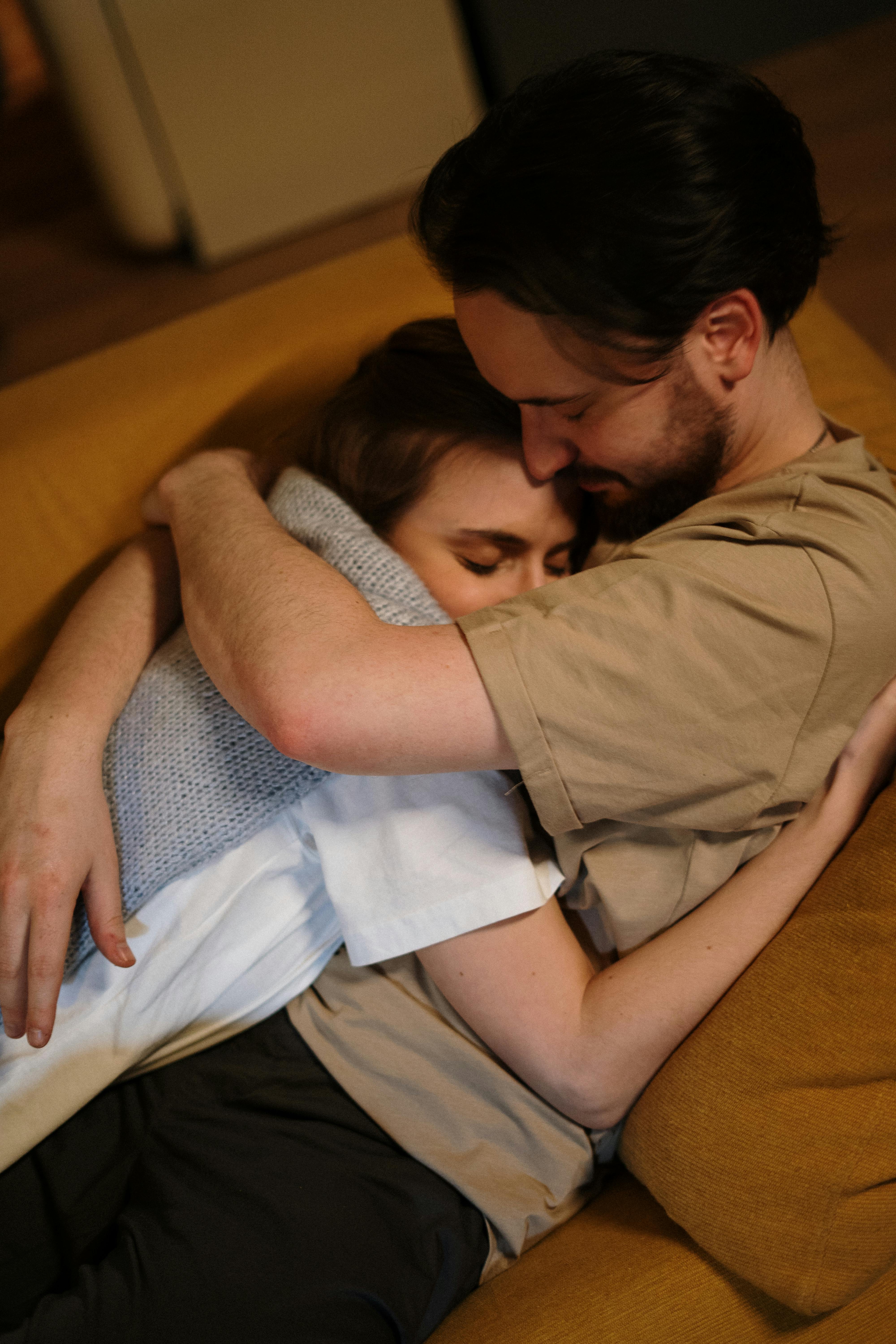 A couple embracing while lying on a couch | Source: Pexels