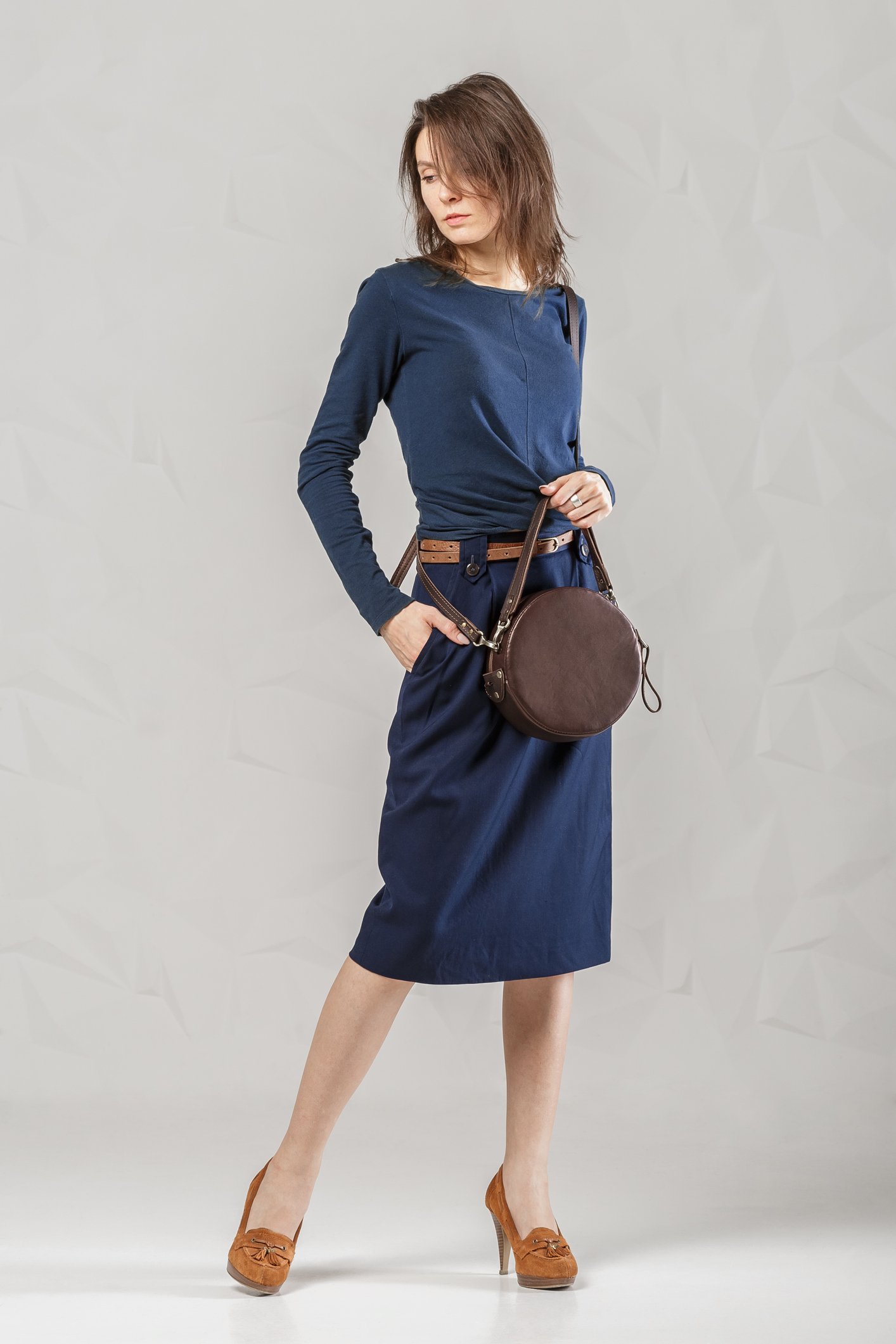 Une femme habiller d'une robe bleu marine portant un sac. | Photo : Getty Images