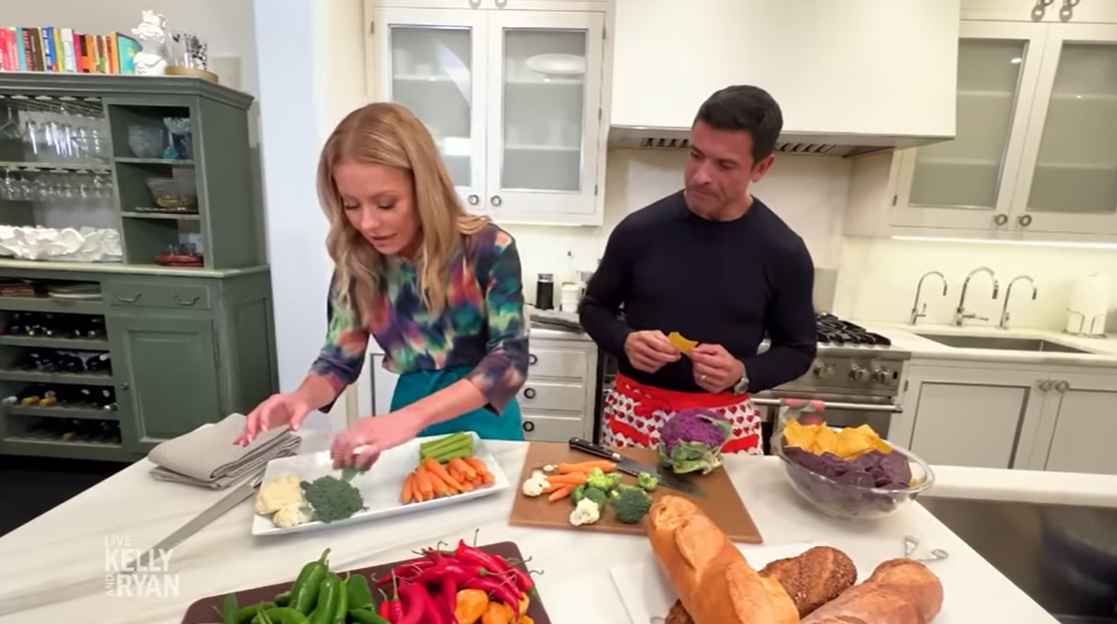 Kelly Ripa and Mark Consuelos prepare a dish in their home kitchen. | Source: YouTube/LiveKellyandMark