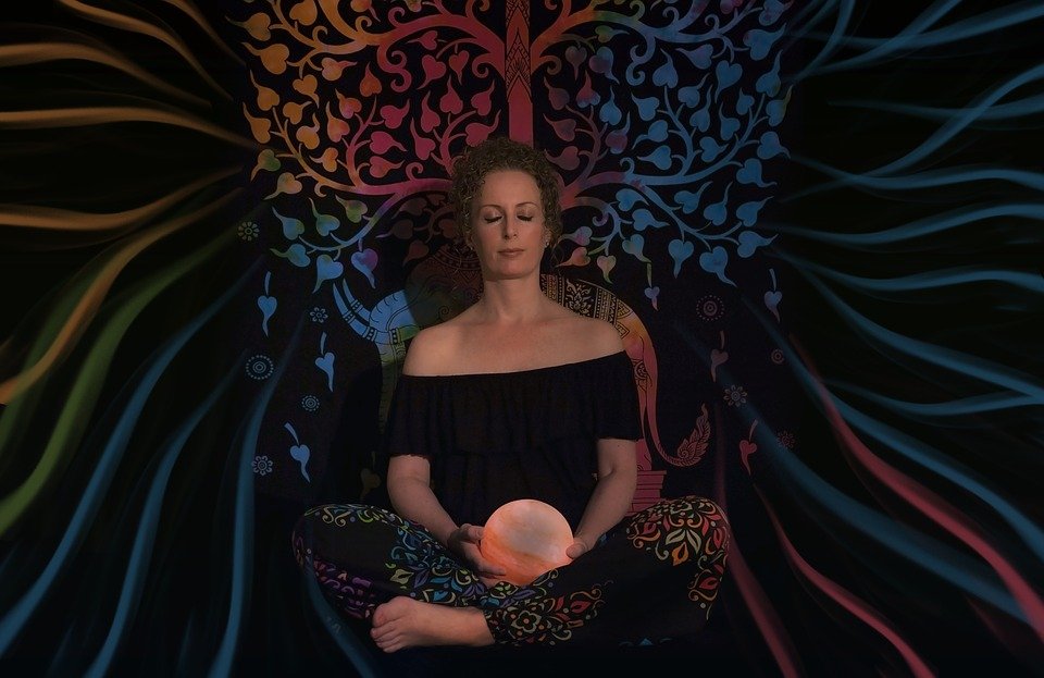 Mujer meditando sosteniendo bola de cristal. | Imagen: Pixabay