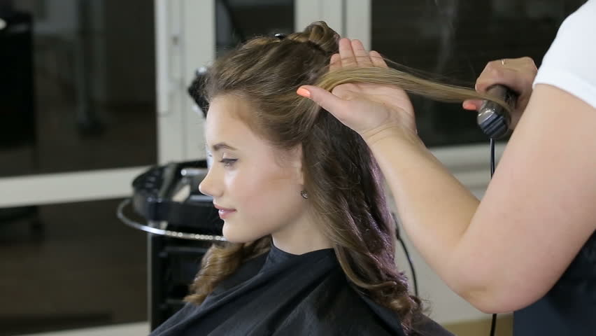 Professional hairstylist curling her client's hair | Photo: Shutterstock