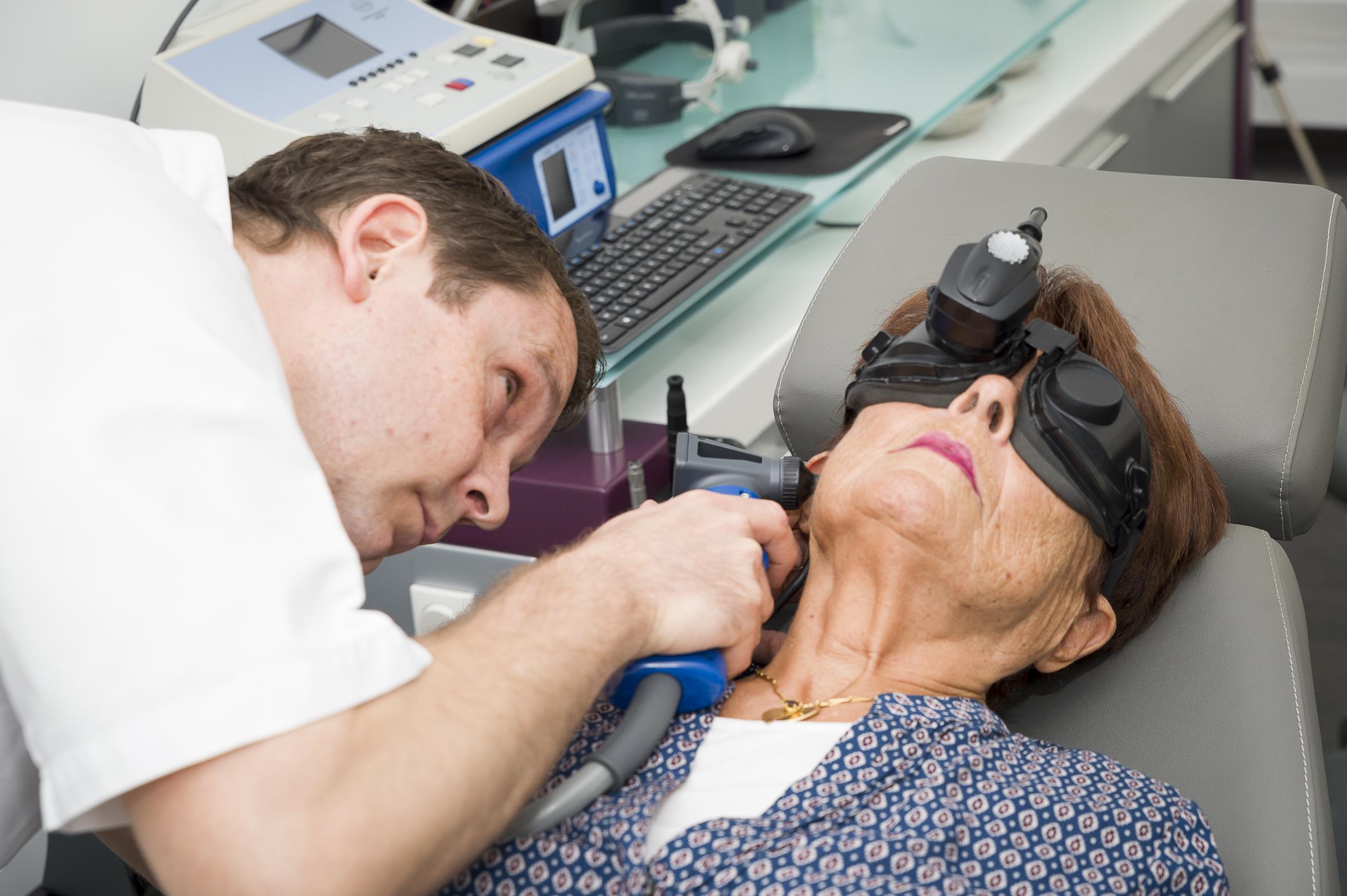 Physician performs an ear examination while patient undergoes balance testing with infrared diagnostic goggles | Source: Getty Images