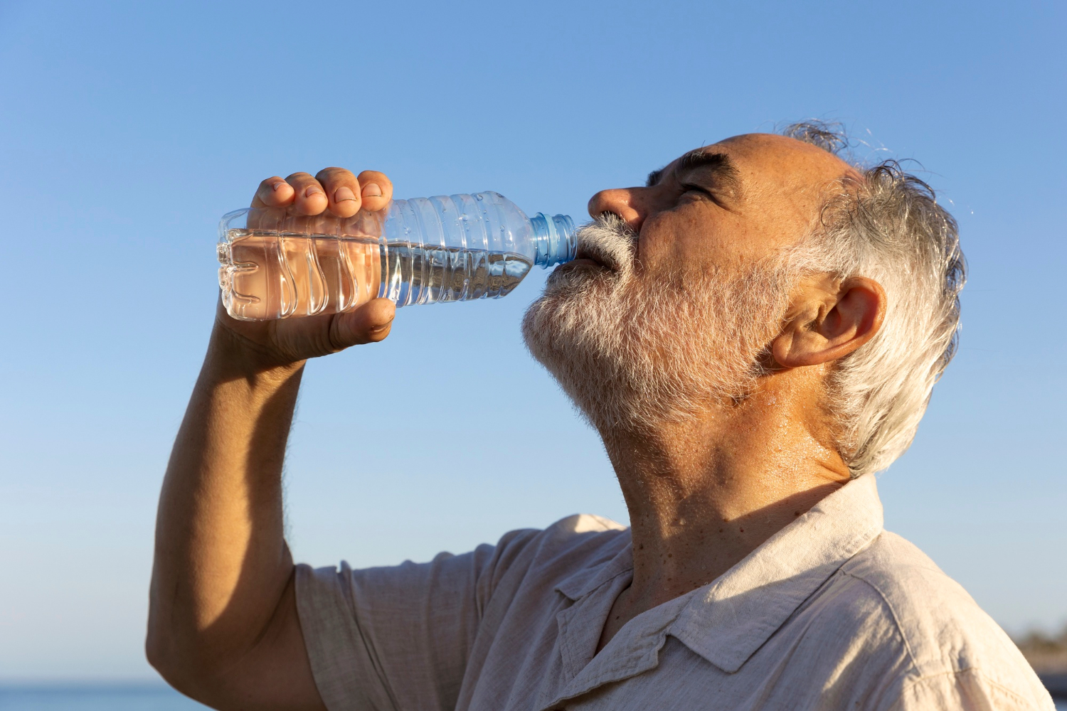 An older man drinking a bottle of water | Source: Freepik