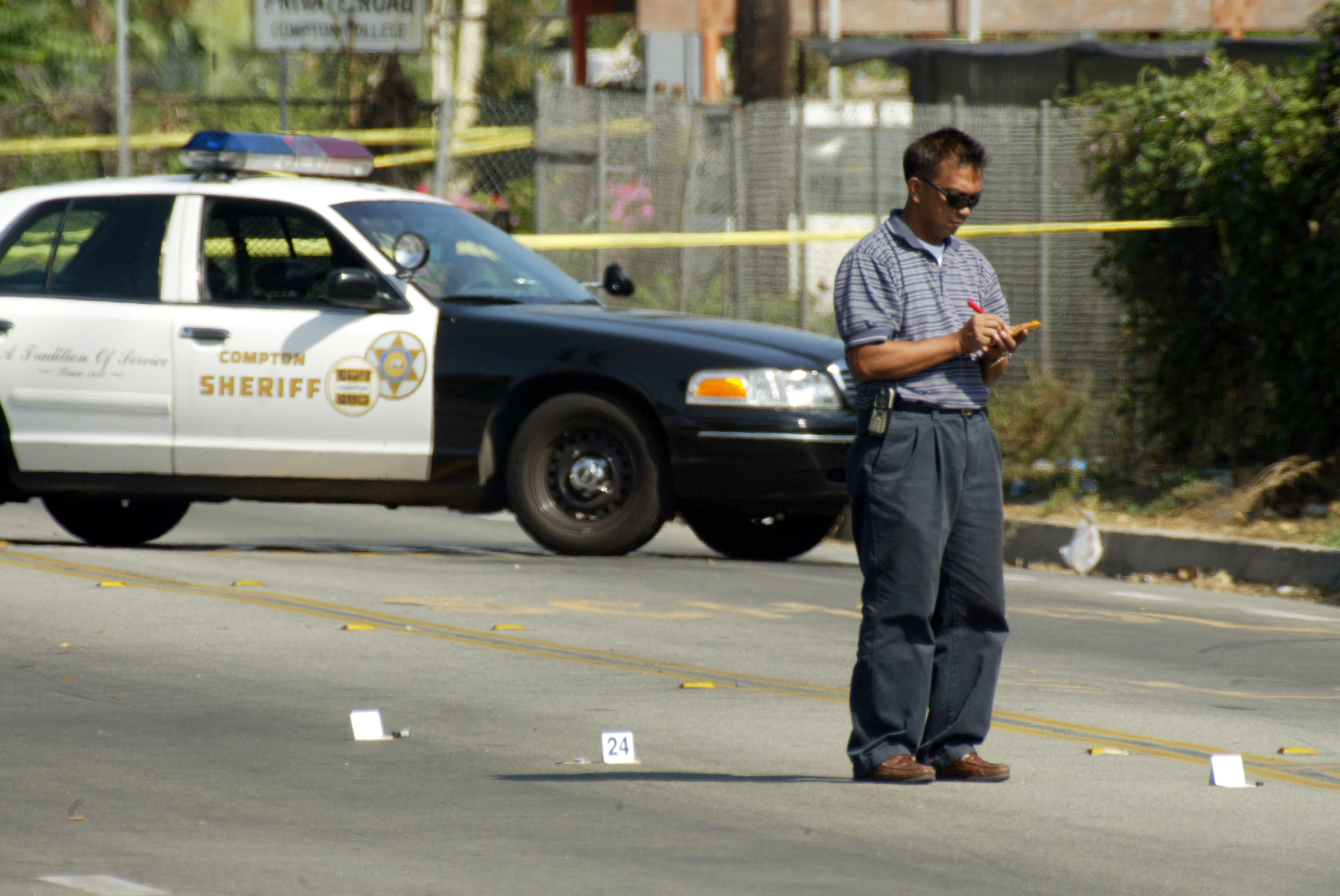 A Los Angeles Police forensic officer examining bullet casings at the crime scene where 31-year-old Yetunde Price was fatally shot on September 14, 2003, in Compton, California. | Source: Getty Images