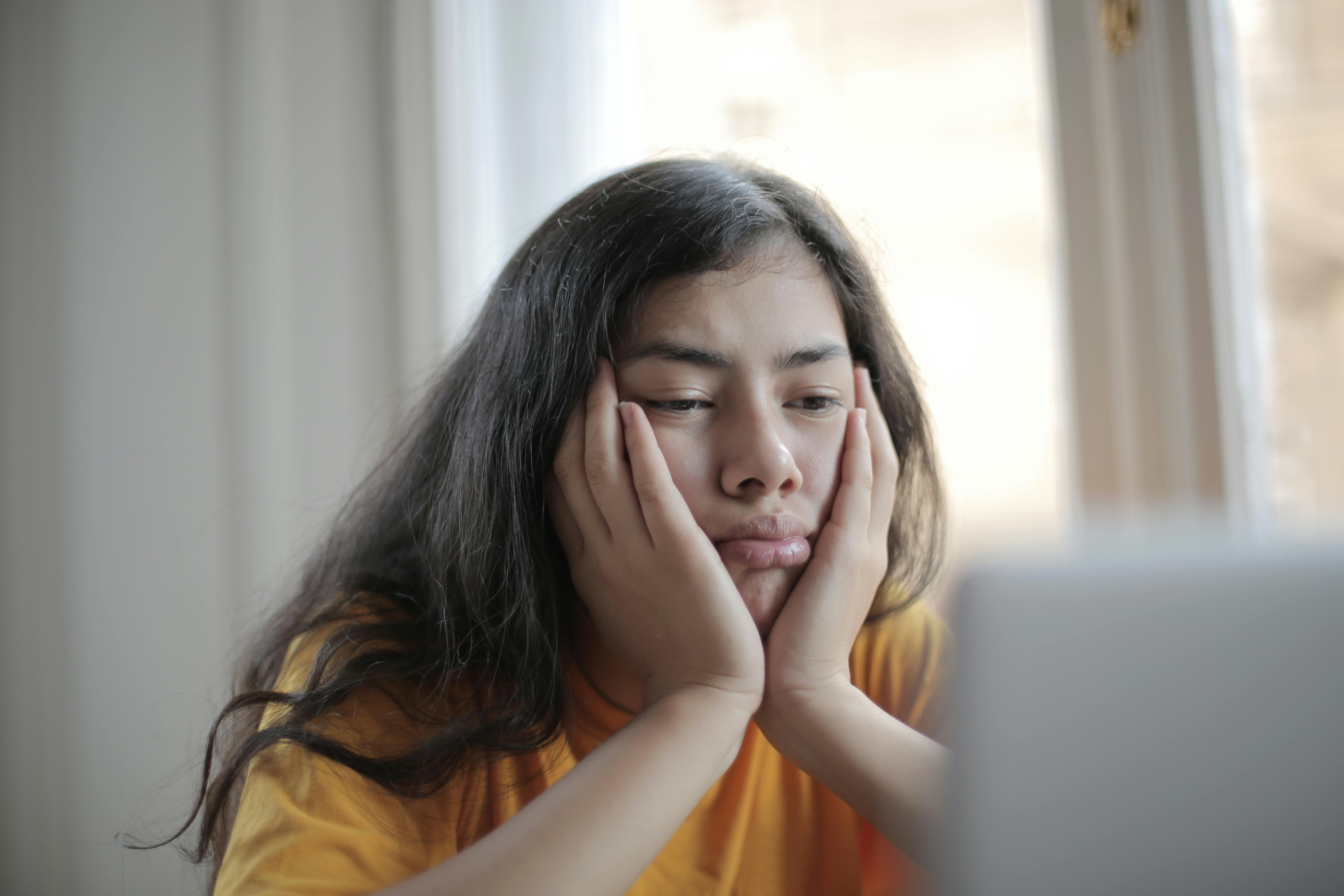 An unhappy girl sitting and looking at a screen | Source: Pexels