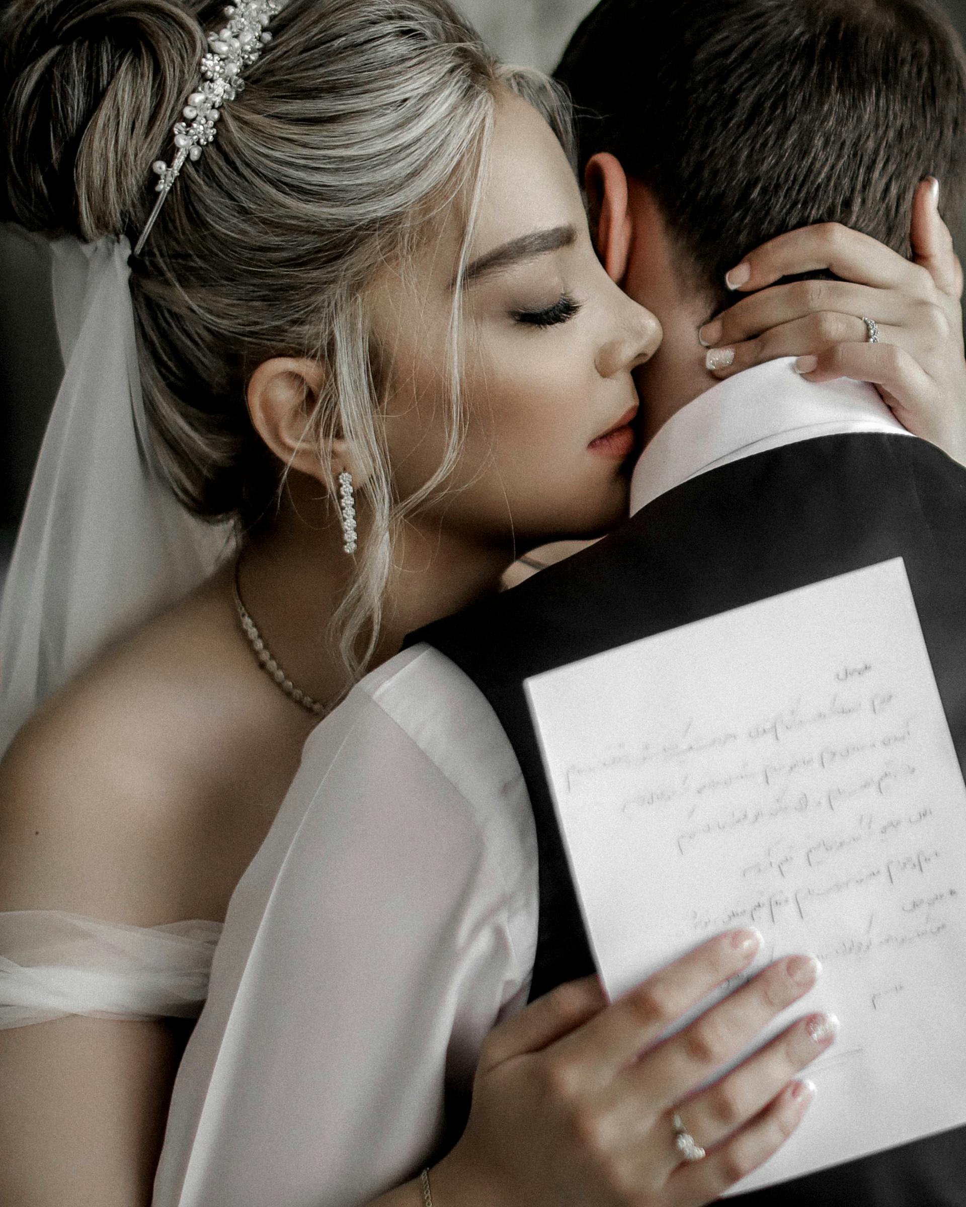A bride hugging a groom while holding a piece of paper | Source: Pexels