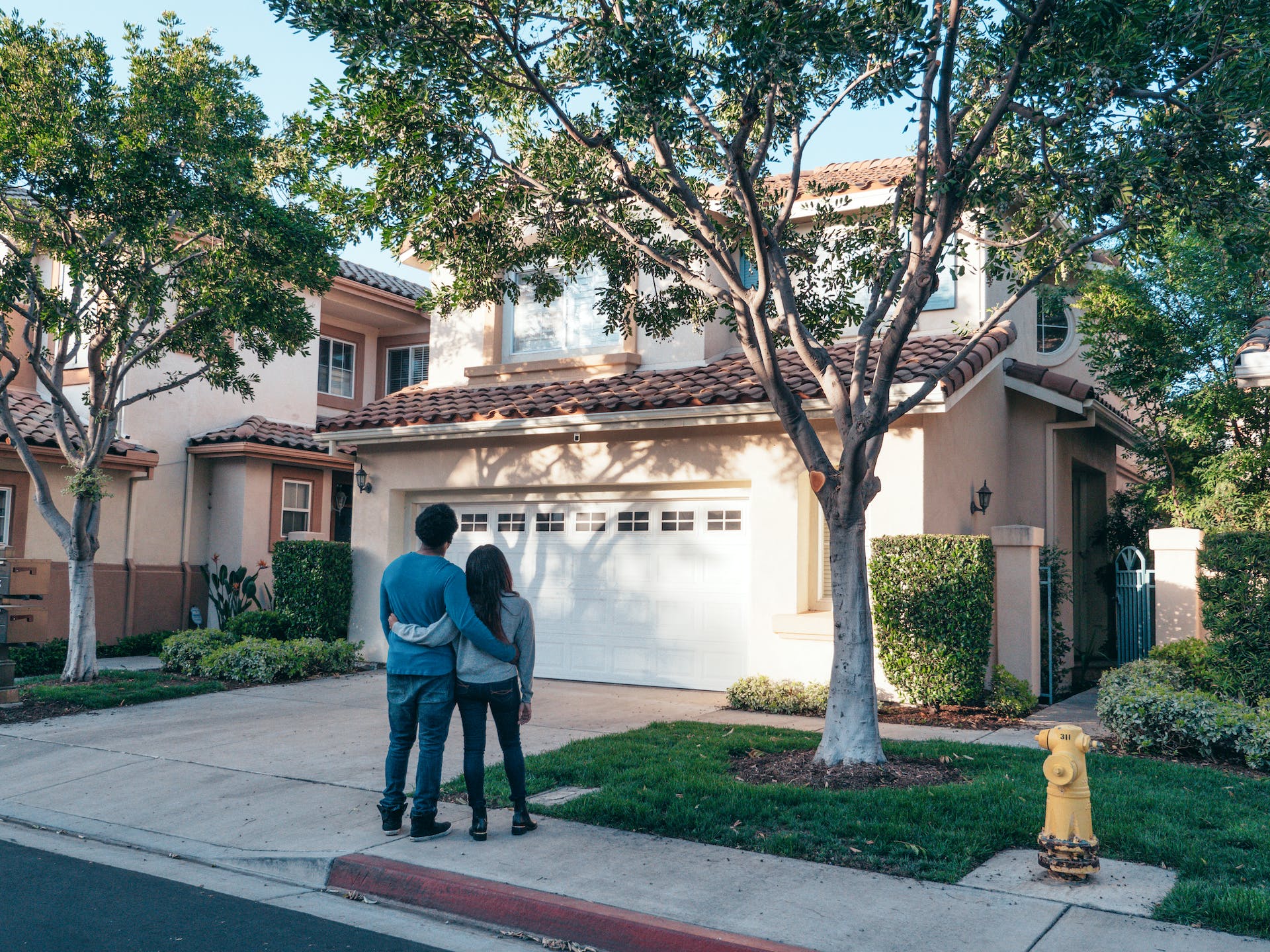 A couple standing in front of their new home | Source: Pexels