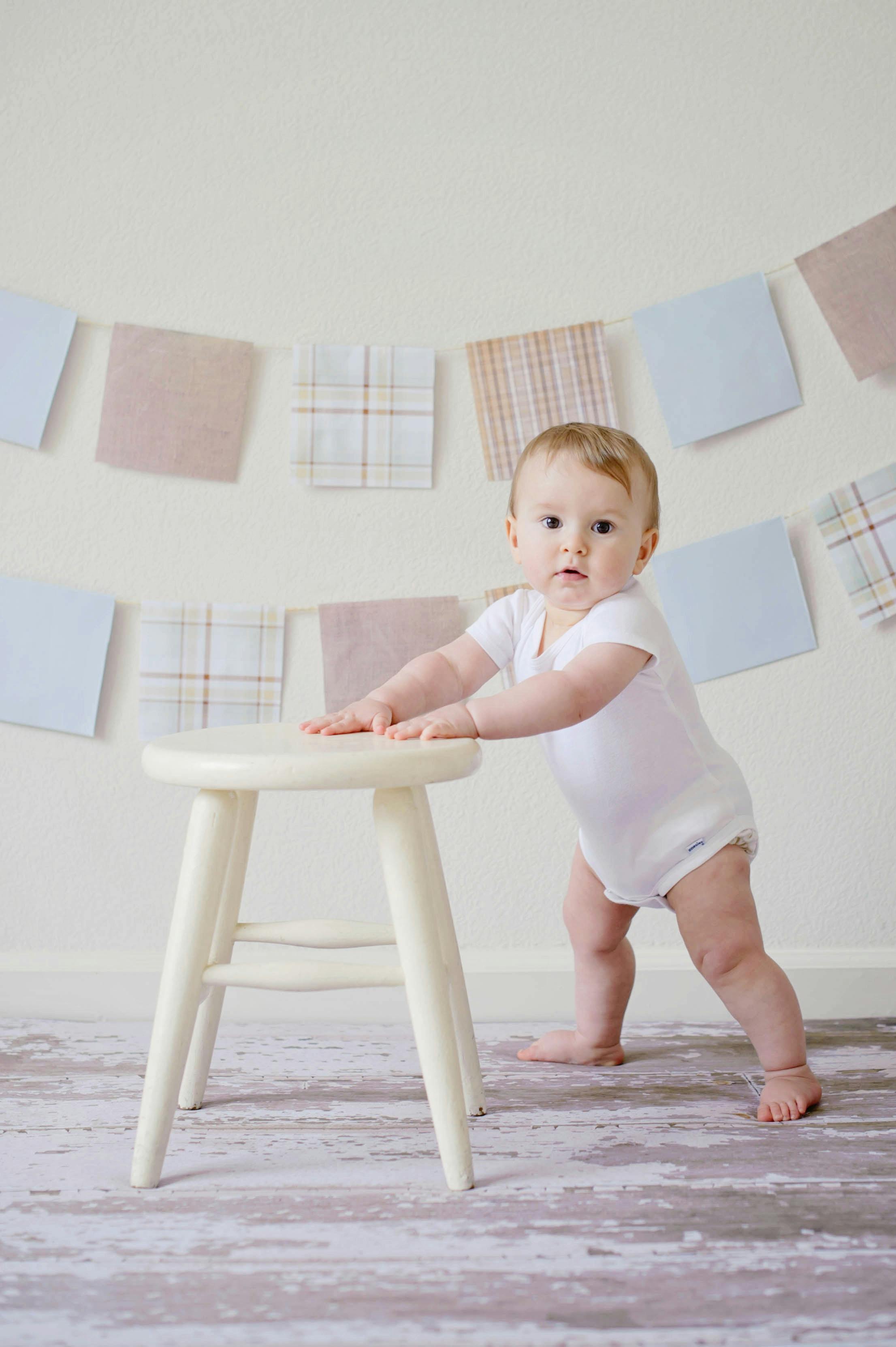 A baby holding on to a stool | Source: Pexels