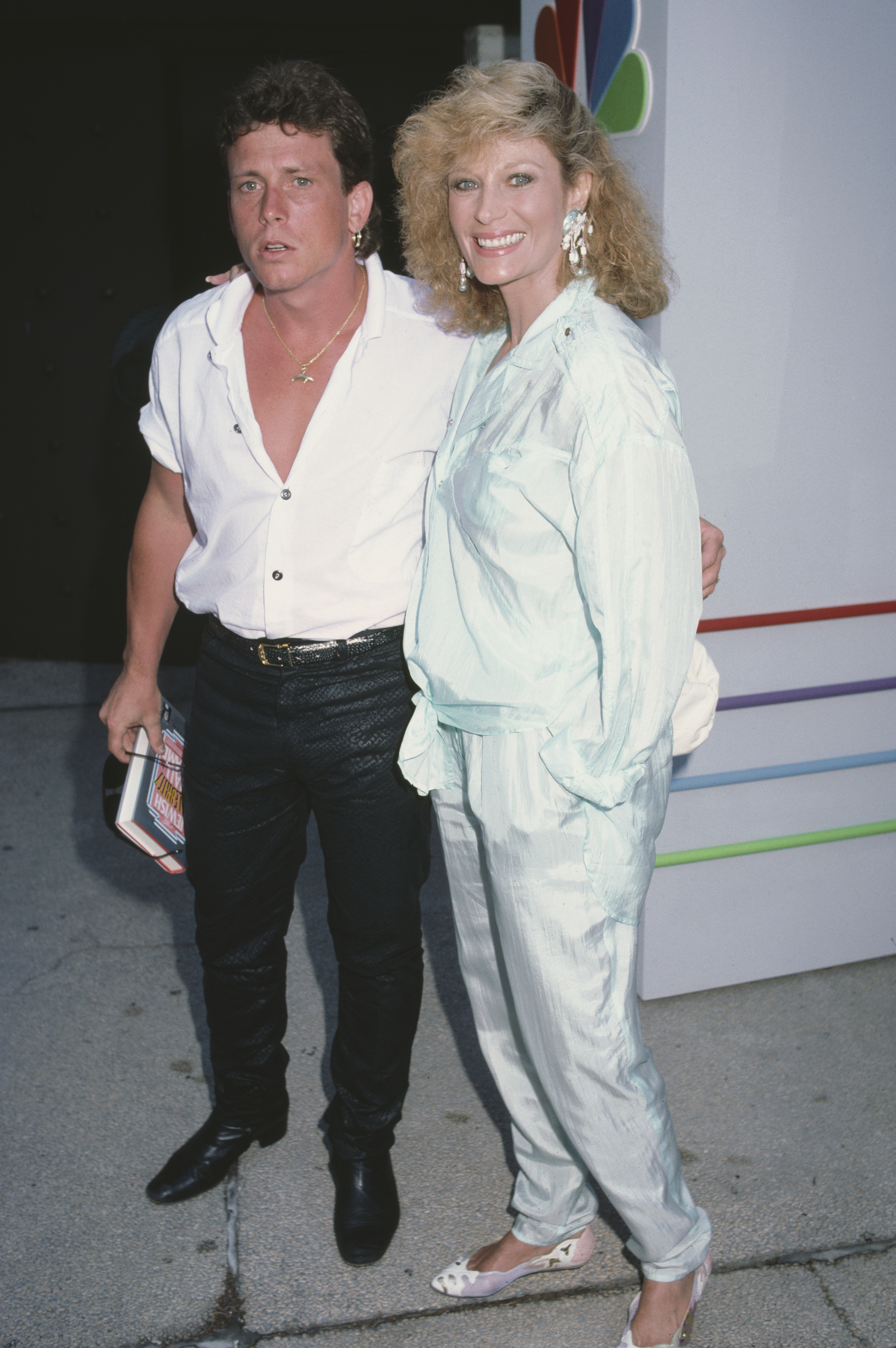 Willie Aames with a white shirt open at the front stands beside an unspecified woman, circa 1995. | Source: Getty Images