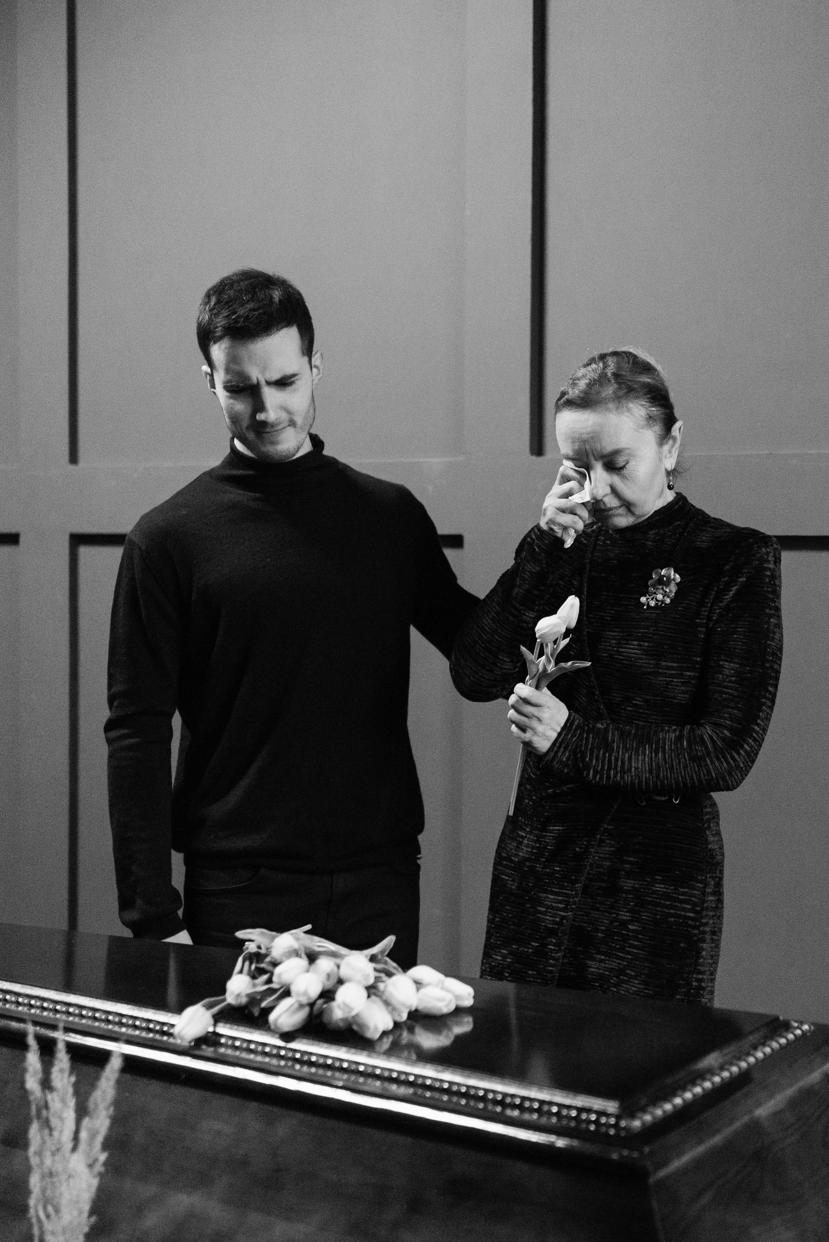 A young man and an elderly woman crying in front of a coffin | Source: Pexels