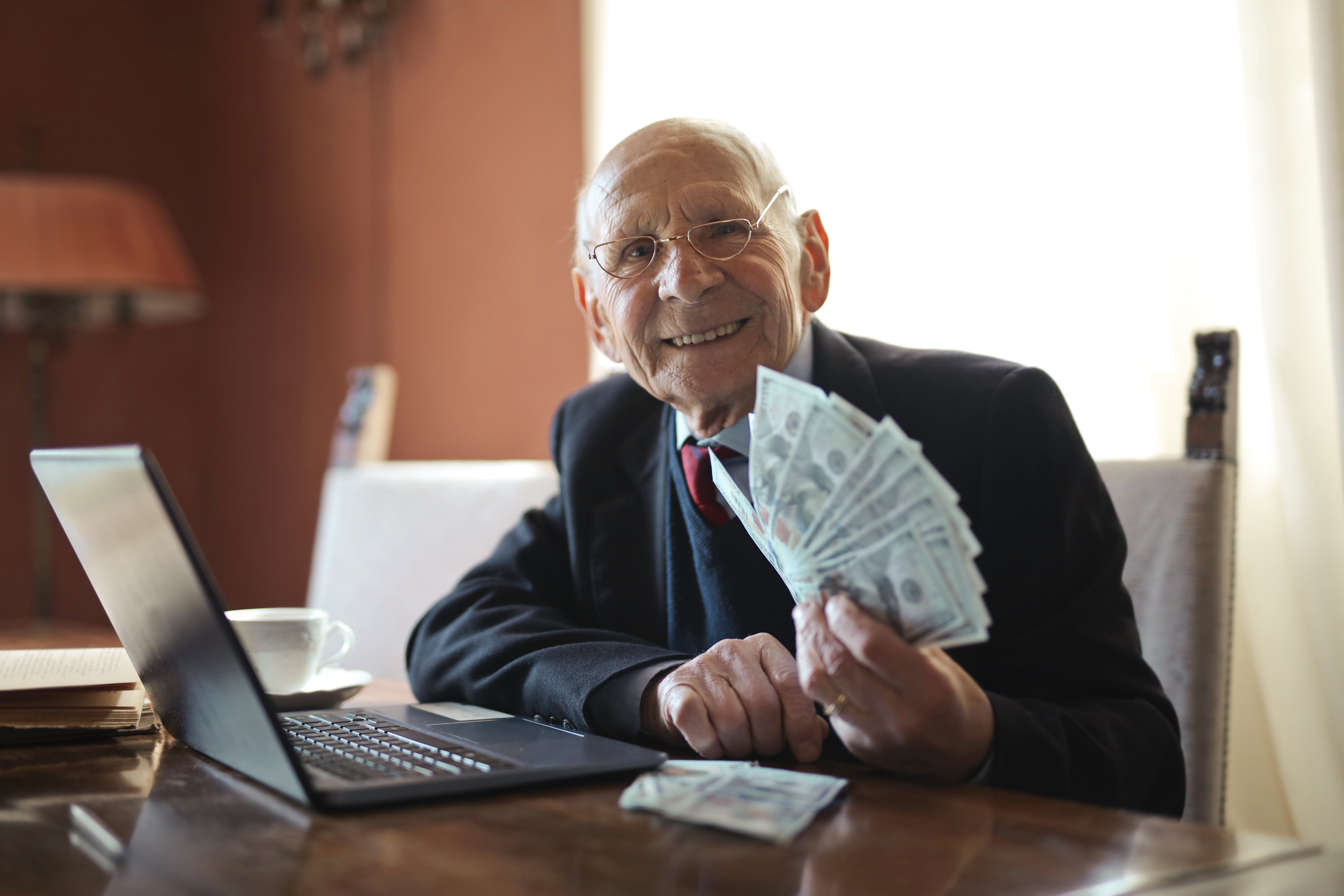 An elderly man smiling while holding money. | Source: Pexels