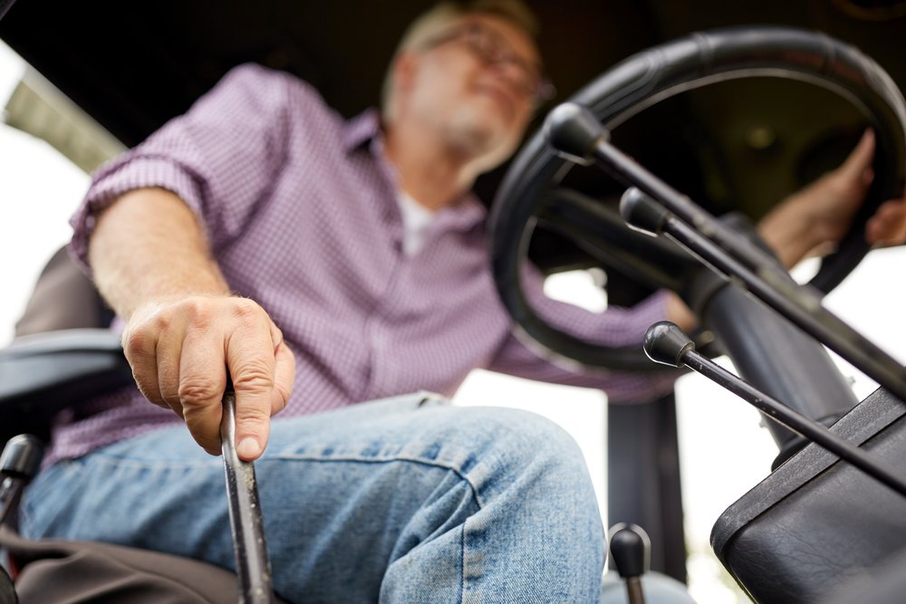 A senior man driving a tractor on a farm | Photo: Shutterstock/Syda Productions