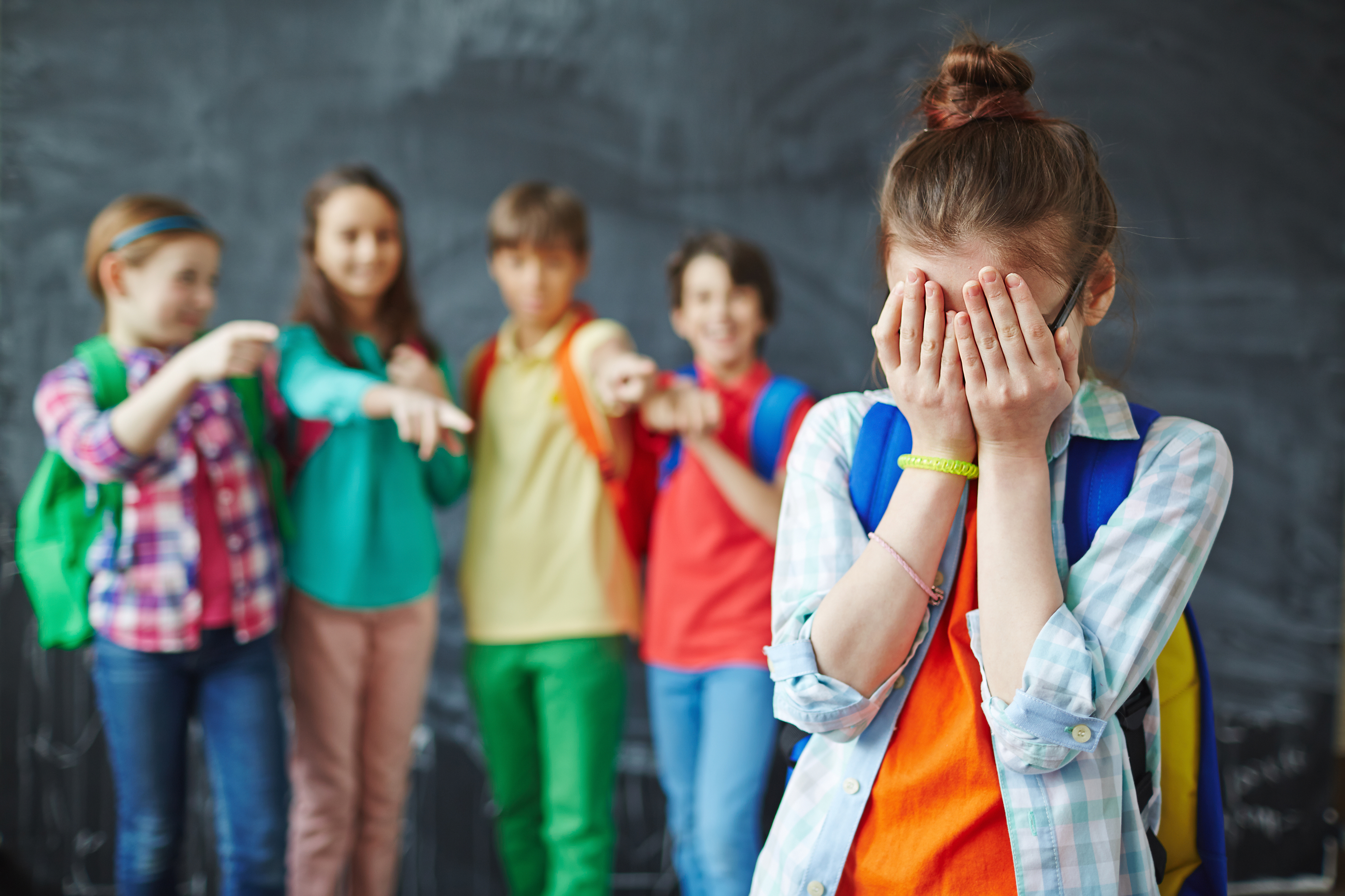 A group of kid bullies and a girl crying | Source: Shutterstock