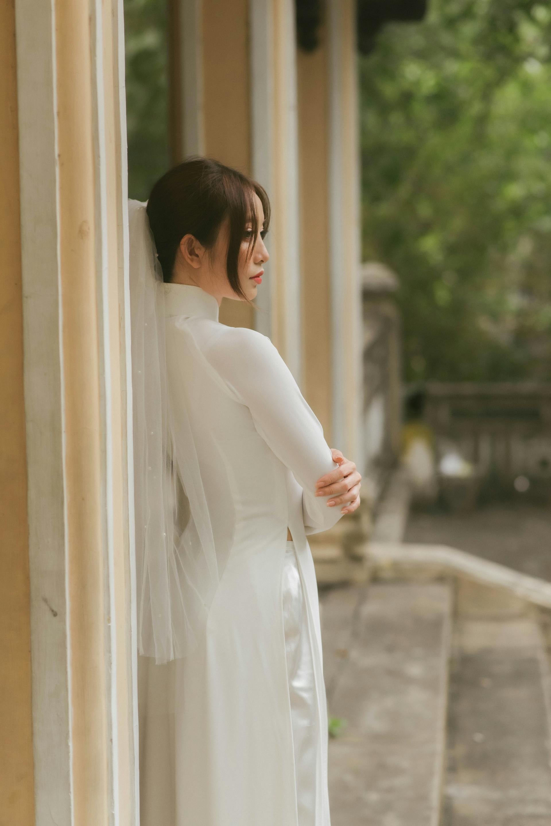 A woman in a bridal dress leaning against a wall | Source: Pexels