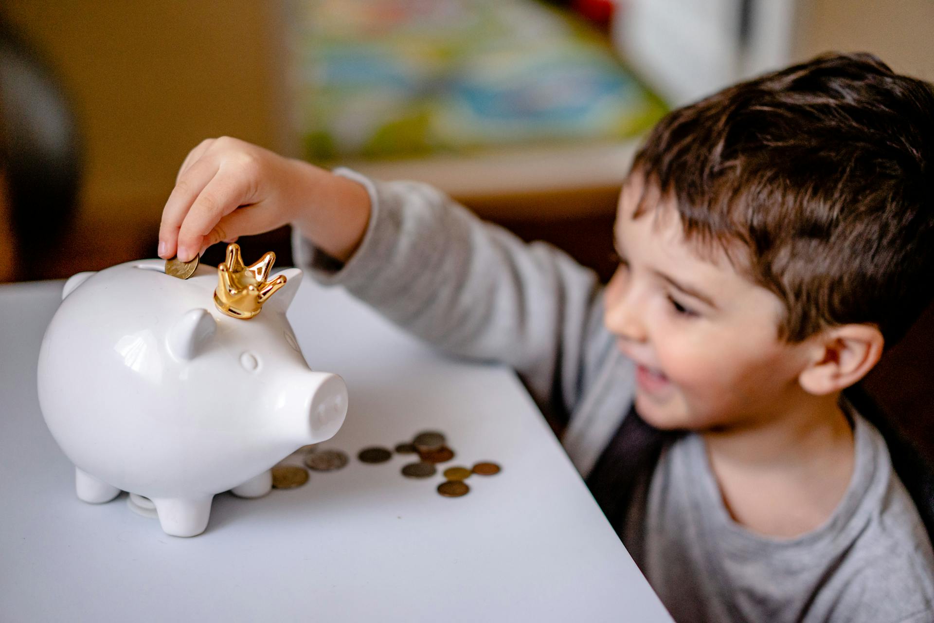 A little boy putting coins in a piggy bank | Source: Pexels