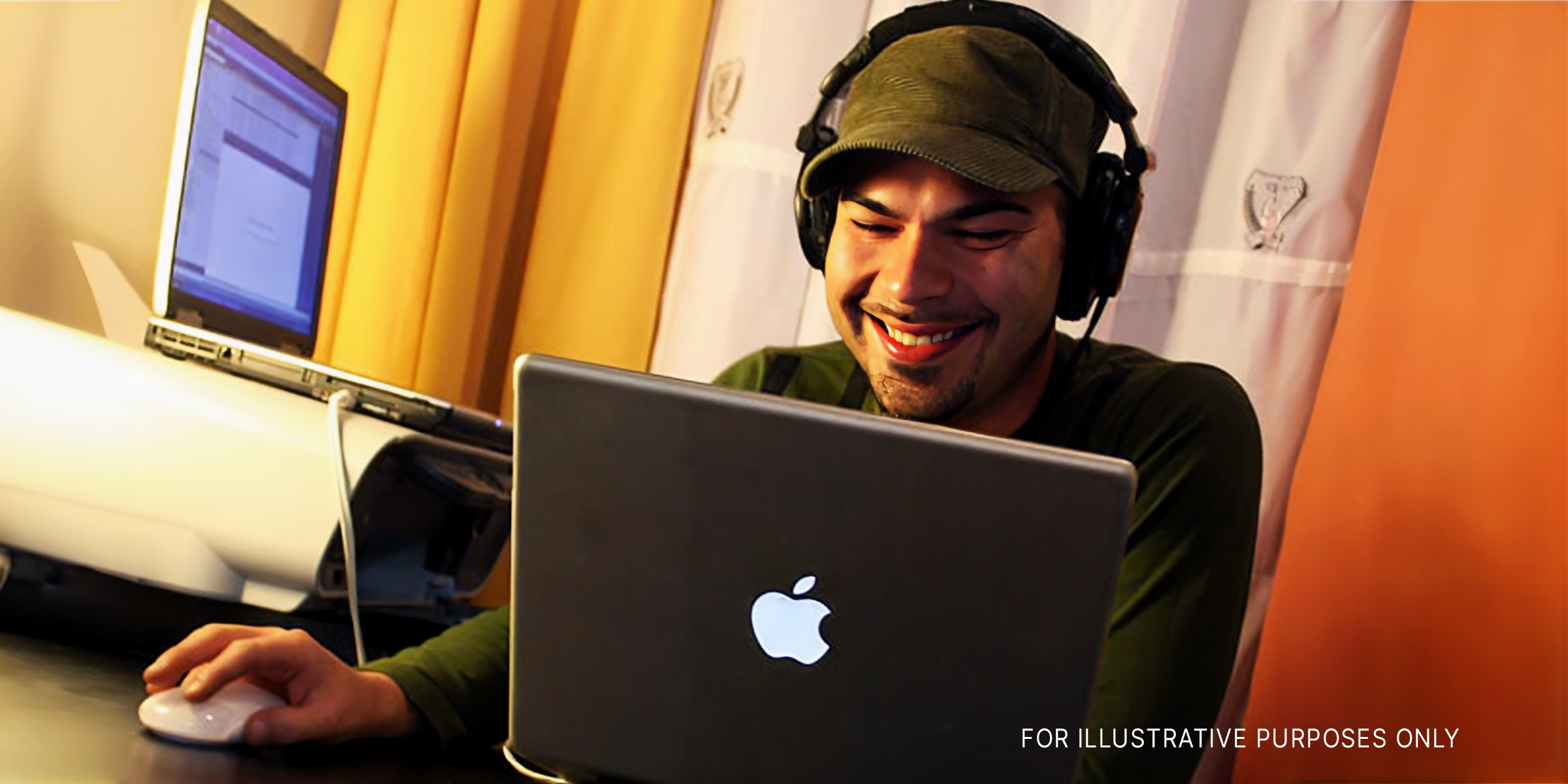 A man wearing headphones smiling at a laptop | Source: Flickr