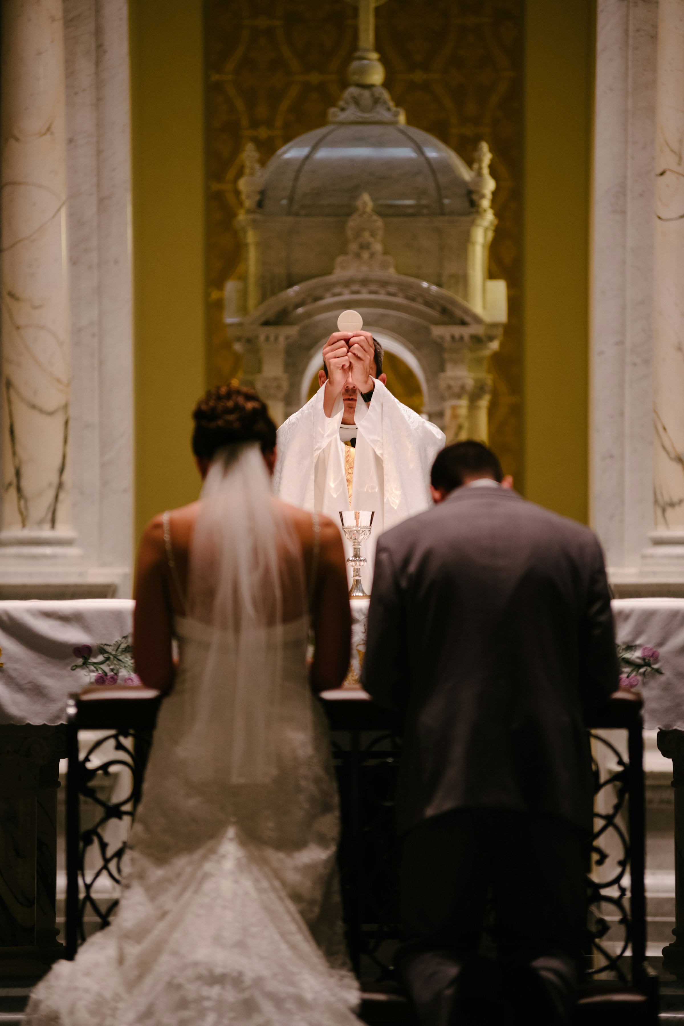 Um casal ajoelhado diante de um padre | Fonte: Unsplash