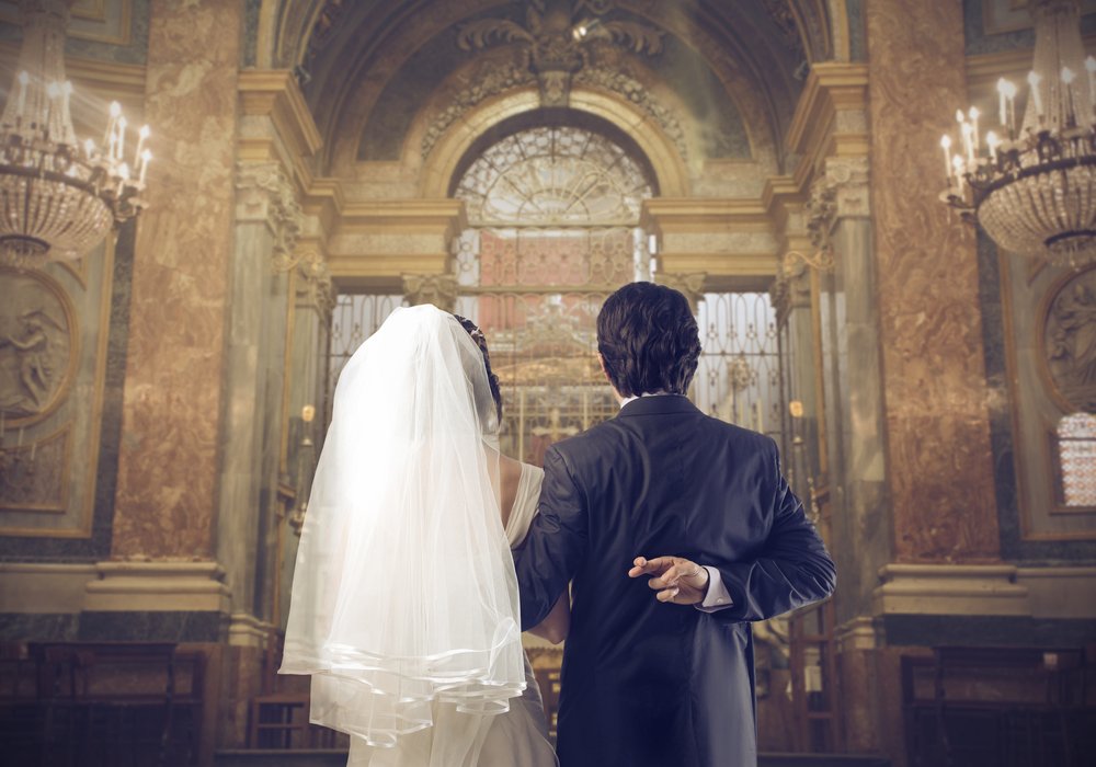 Novio cruzando los dedos detrás de la espalda al casarse. | Foto: Shutterstock