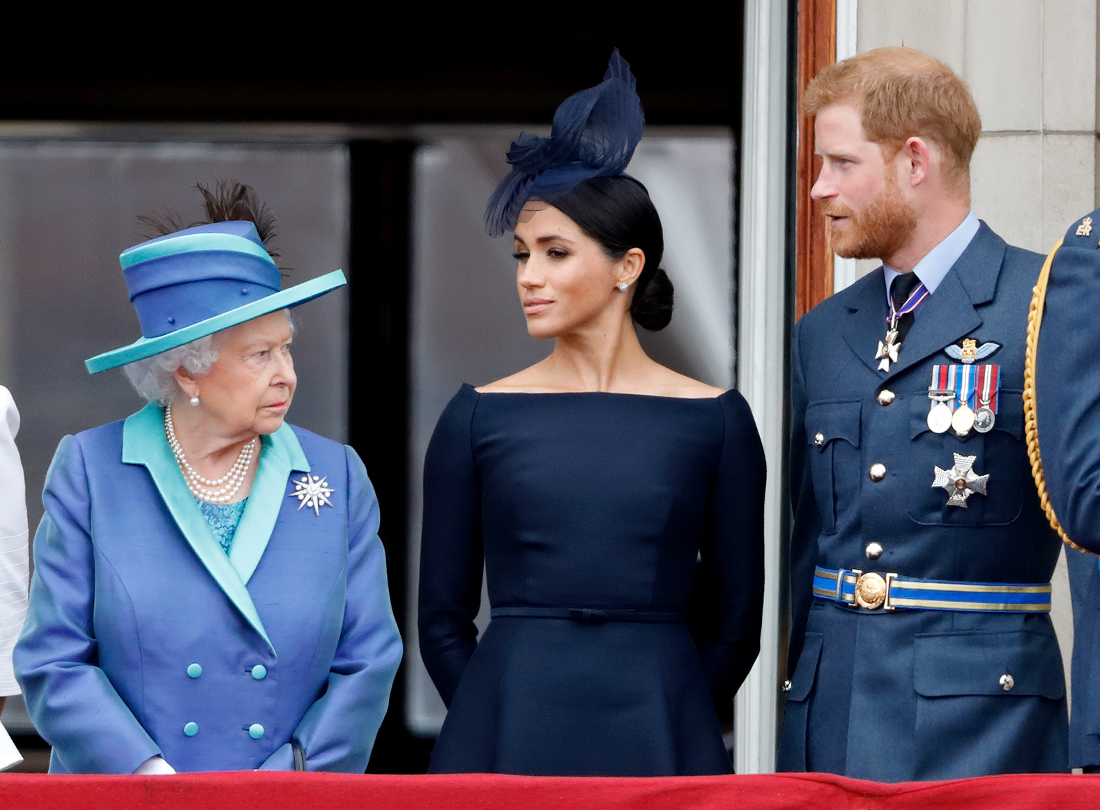Queen Elizabeth II stood alongside Meghan, Duchess of Sussex, and Prince Harry as they observed the RAF centenary flypast from the balcony of Buckingham Palace on 10 July 2018, a moment steeped in royal tradition and national pride. Positioned together above the crowds, the trio reflected a rare public alignment, with the late monarch's composed presence anchoring the scene.