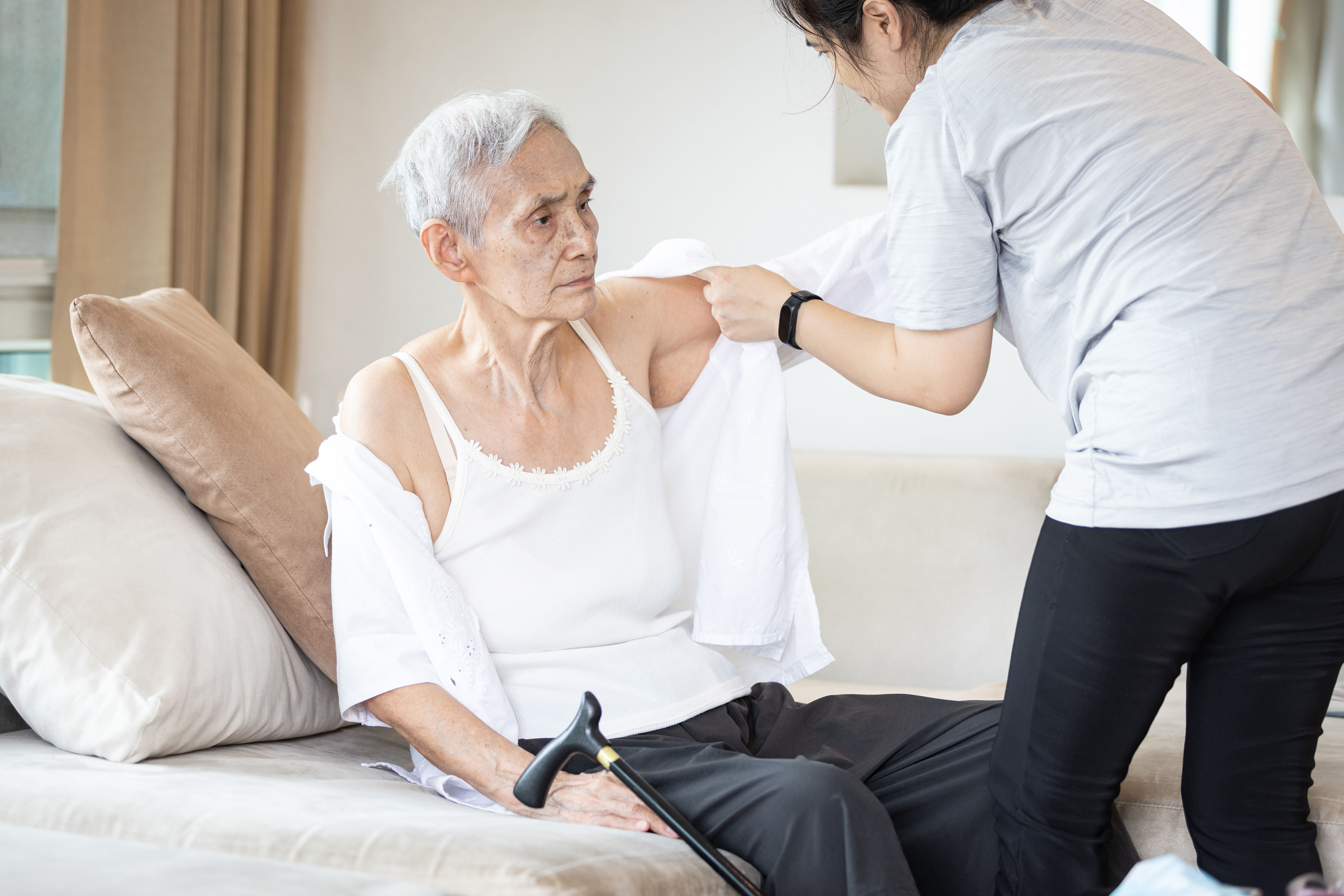 A nurse helping an elderly lady get dressed | Source: Shutterstock