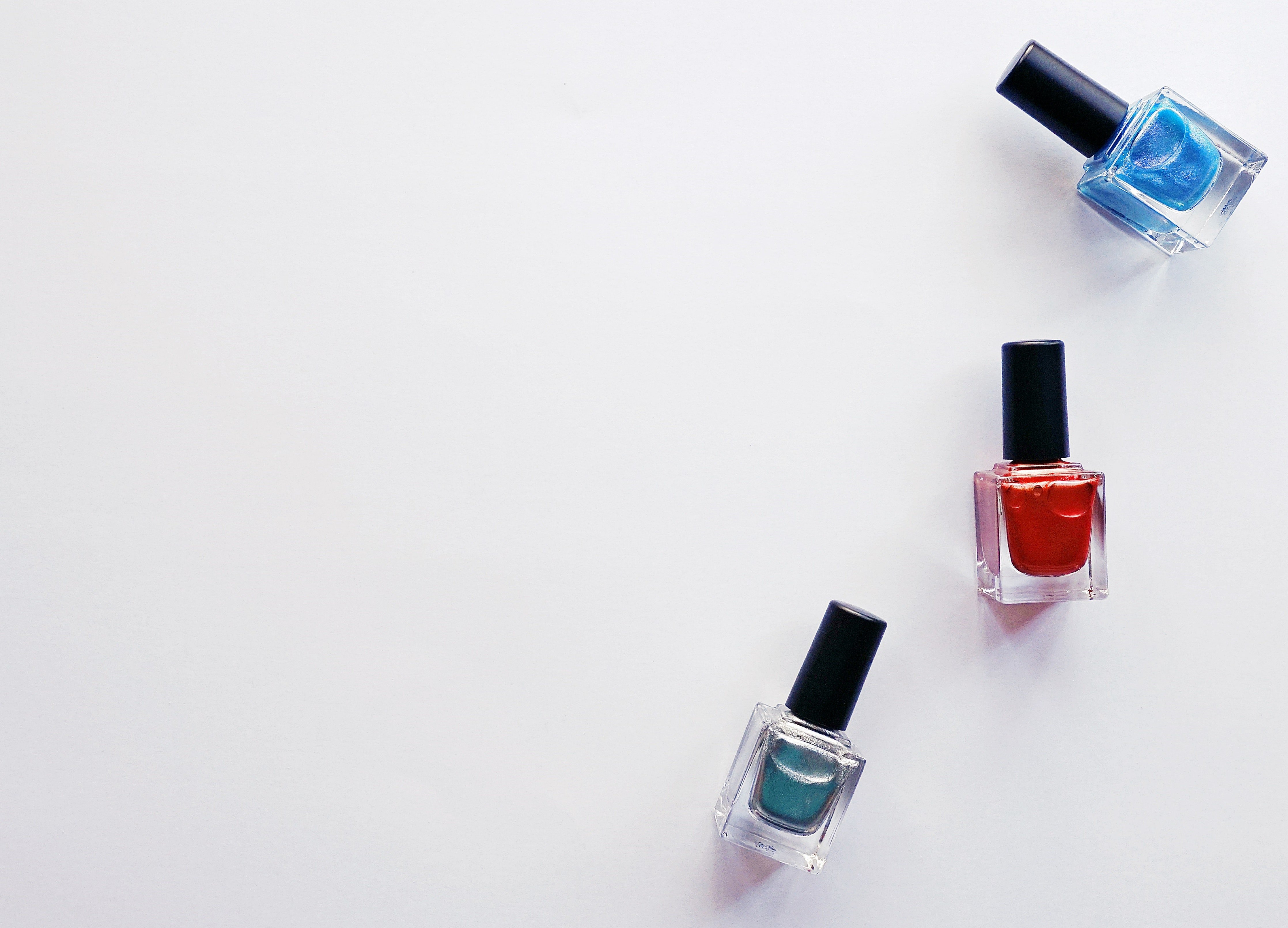 Three bottles of nail polish on a white background. | Photo: Pexels/ Suzy Hazelwood