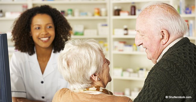 Un couple de personnes âgées passe devant une pharmacie tout en discutant de leur désir de se marier