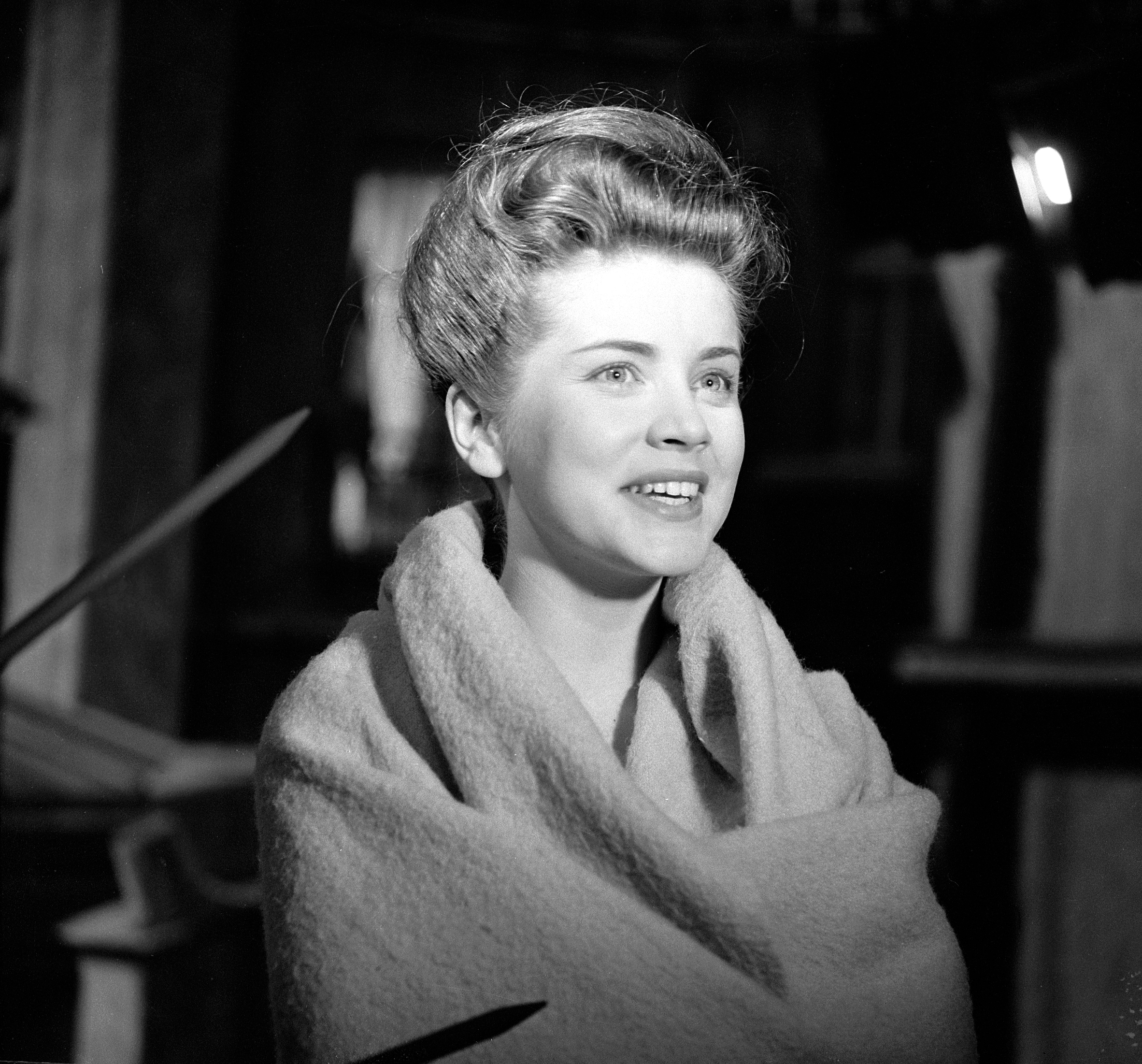 Dolores Hart smiles while wrapped in a blanket during the filming of the CBS television Playhouse 90 production of "To the Sound of Trumpets" on February 8, 1960. | Source: Getty Images