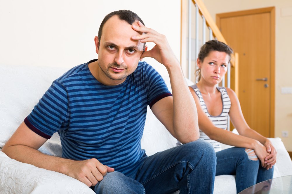 A man looks away from his wife in frustration after having an argument with her | Photo: Shutterstock/Iakov Filimonov