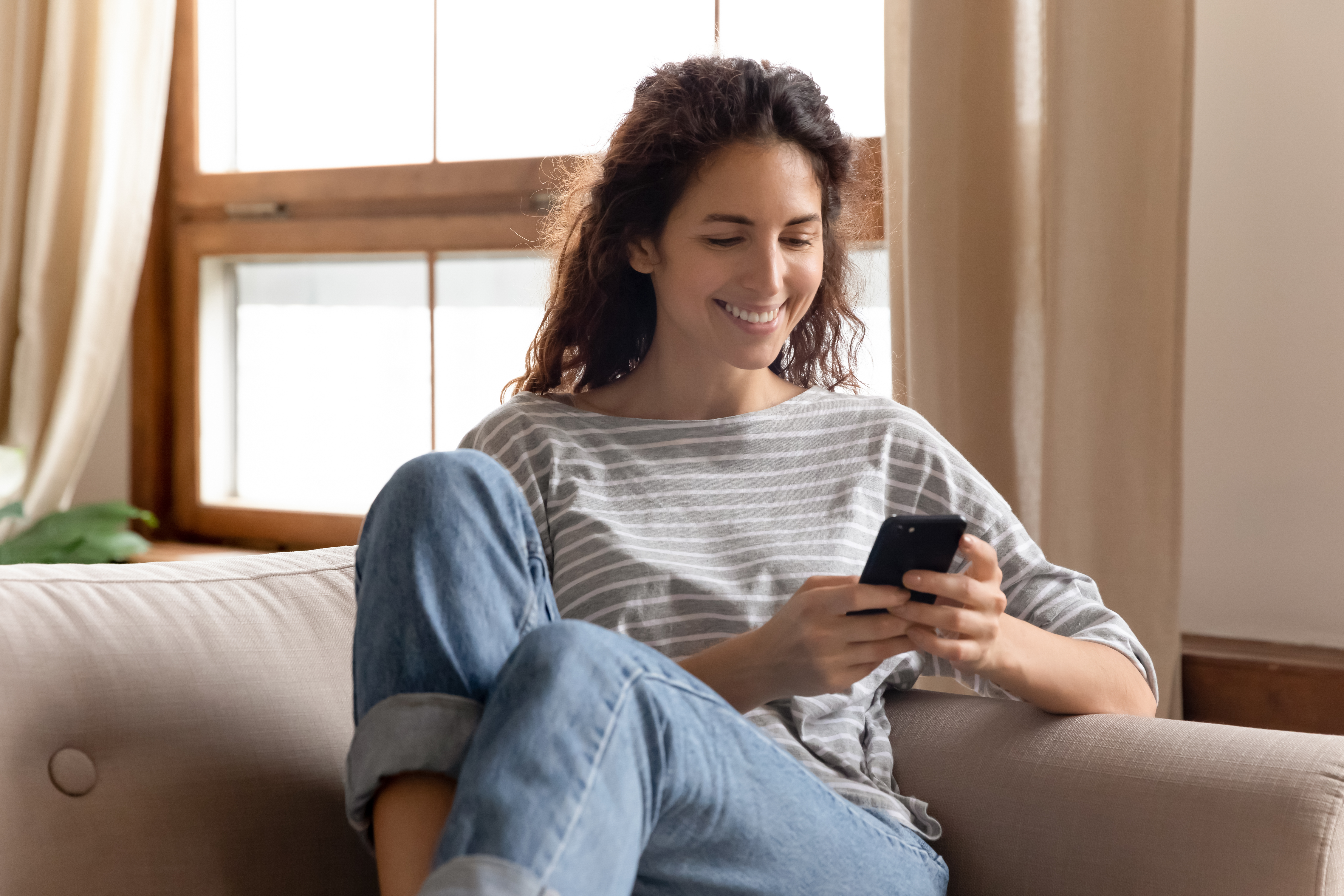 A woman smiling while looking at her cellphone | Source: Shutterstock