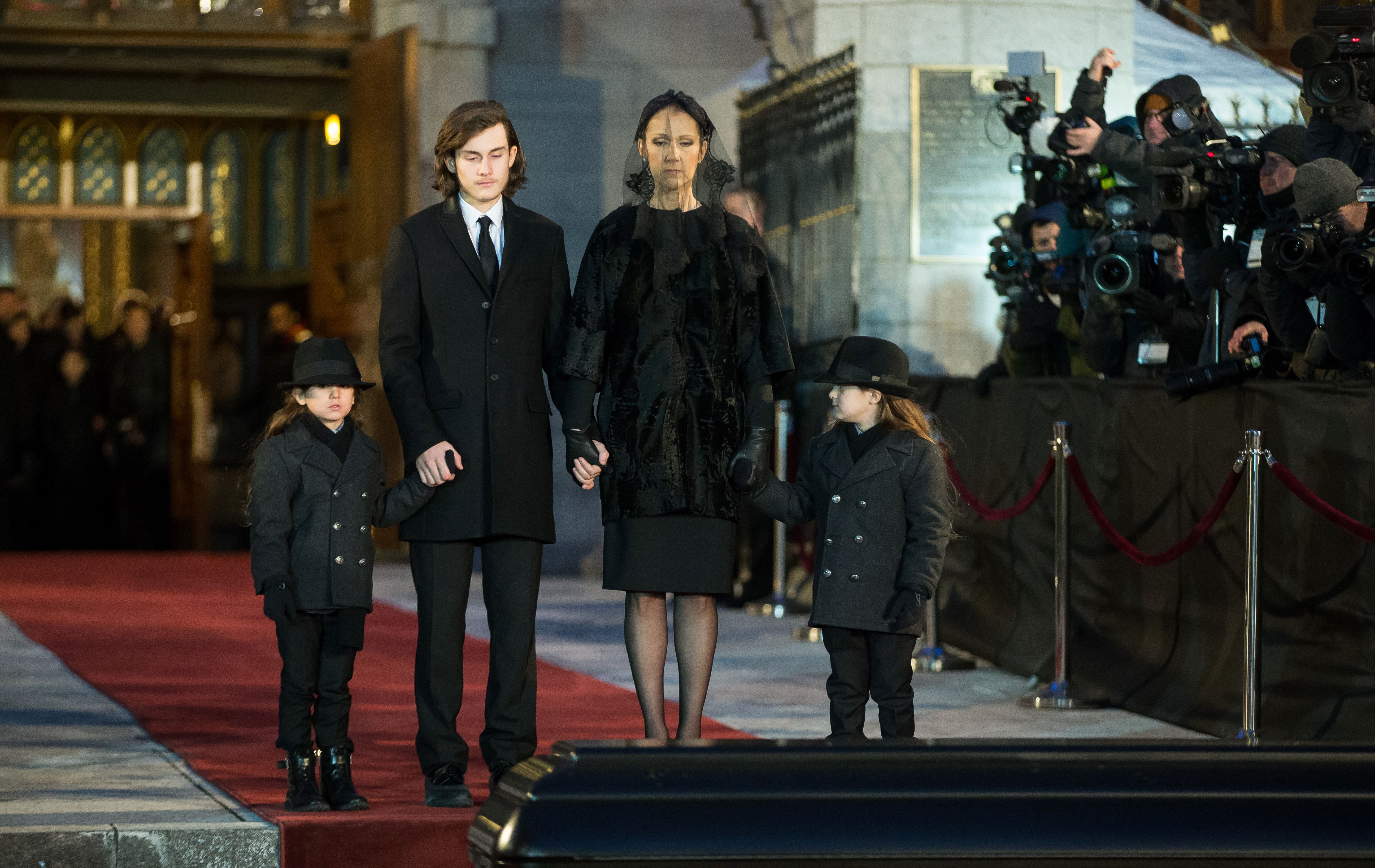 Céline Dion and her sons René-Charle, Eddy, and Nelson, pause to view the casket of René Angélil following his funeral service in Montreal, Quebec, on January 22, 2016. | Source: Getty Images