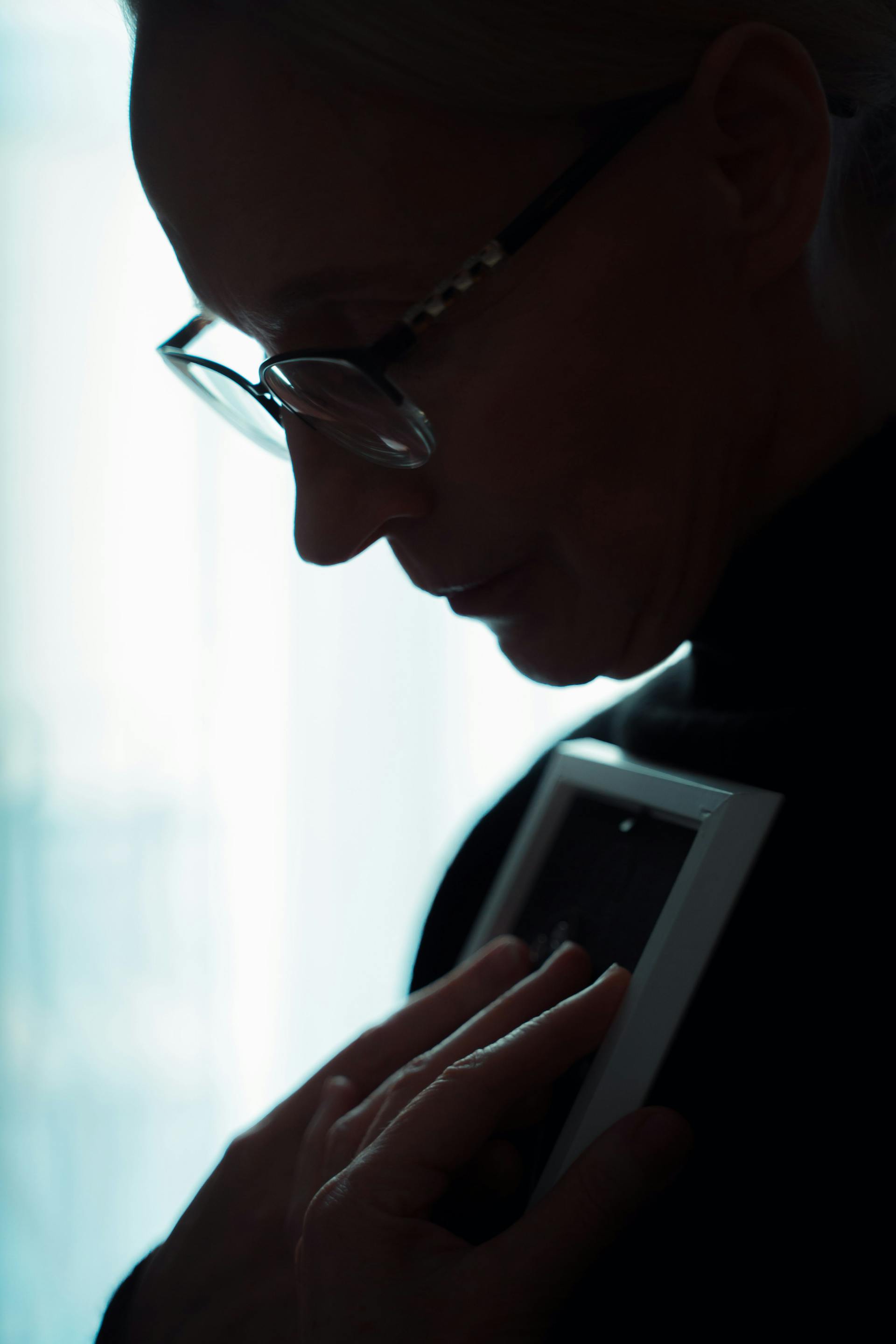 A silhouette of a grieving woman holding a photo frame | Source: Pexels