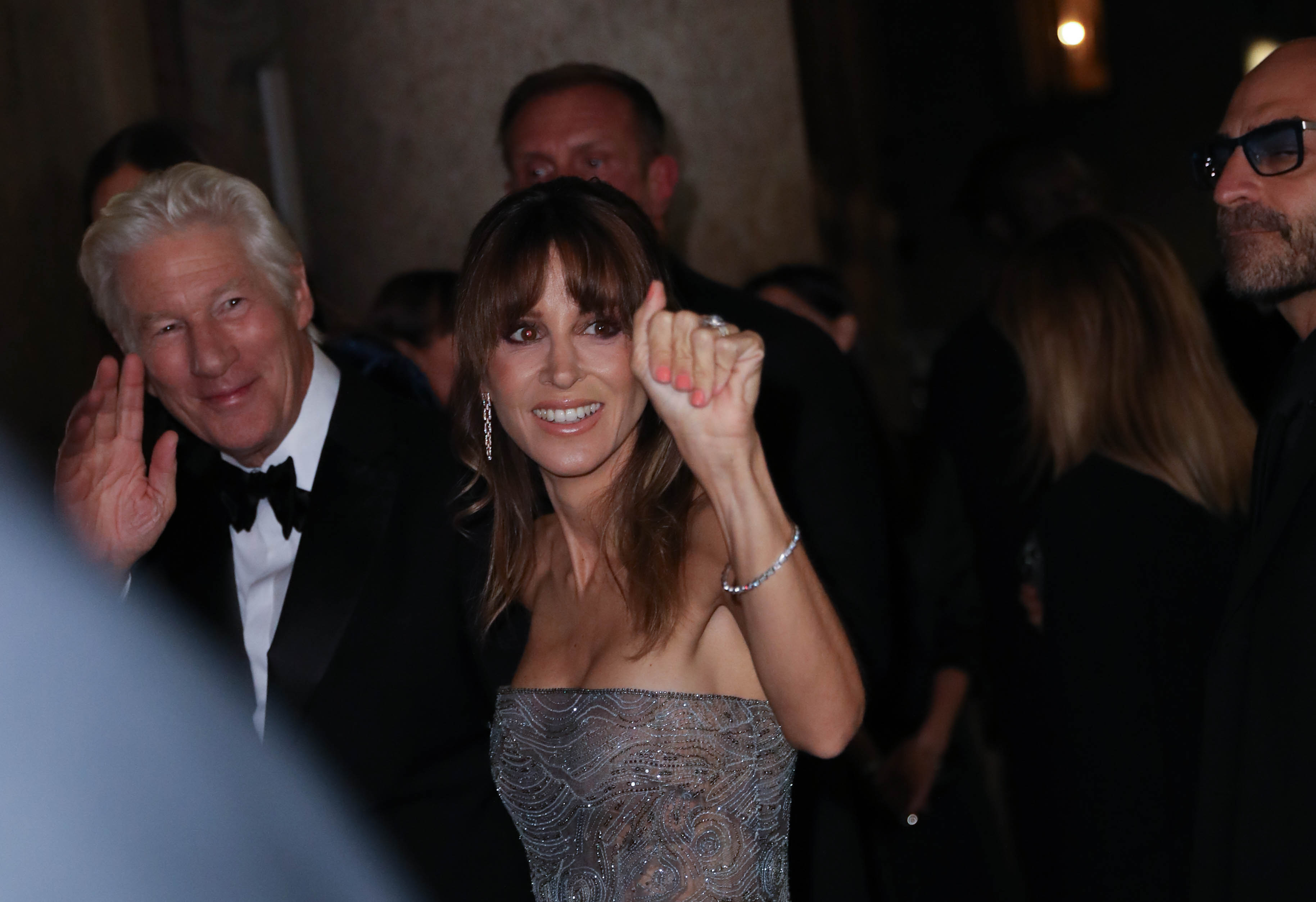 Richard Gere and Alejandra Silva share cheerful waves with fans as they arrive, lighting up the entrance with warmth, glamor, and undeniable star power.