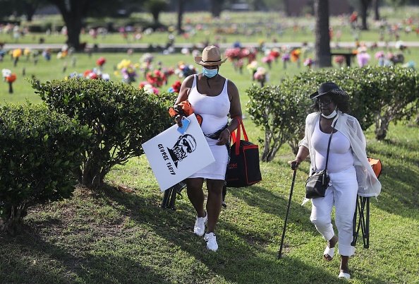 A woman carries a poster of George Floyd after viewing his funeral procession to Houston Memorial Gardens Cemetery for burial on June 9, 2020 in Pearland, Texas | Photo: Getty Images