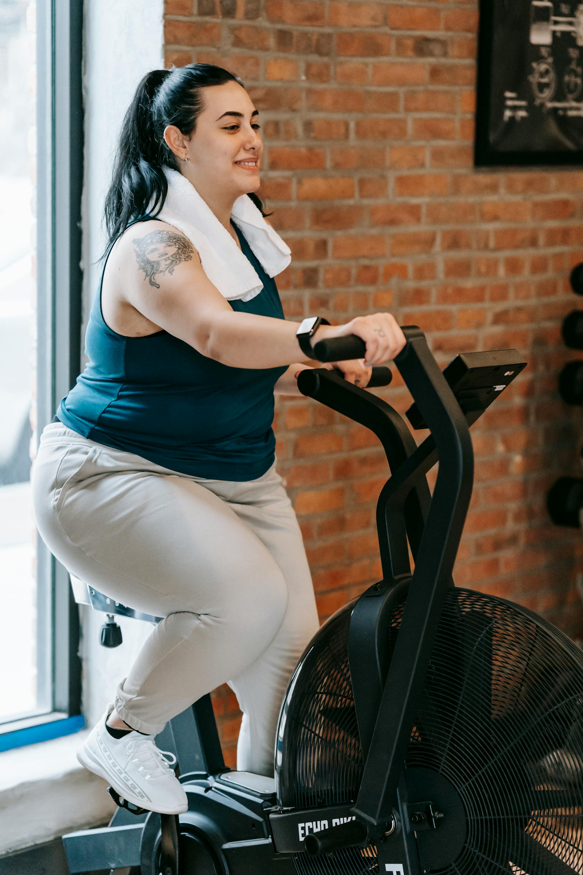 A plus-size woman on a cross trainer machine in a gym | Source: Pexels