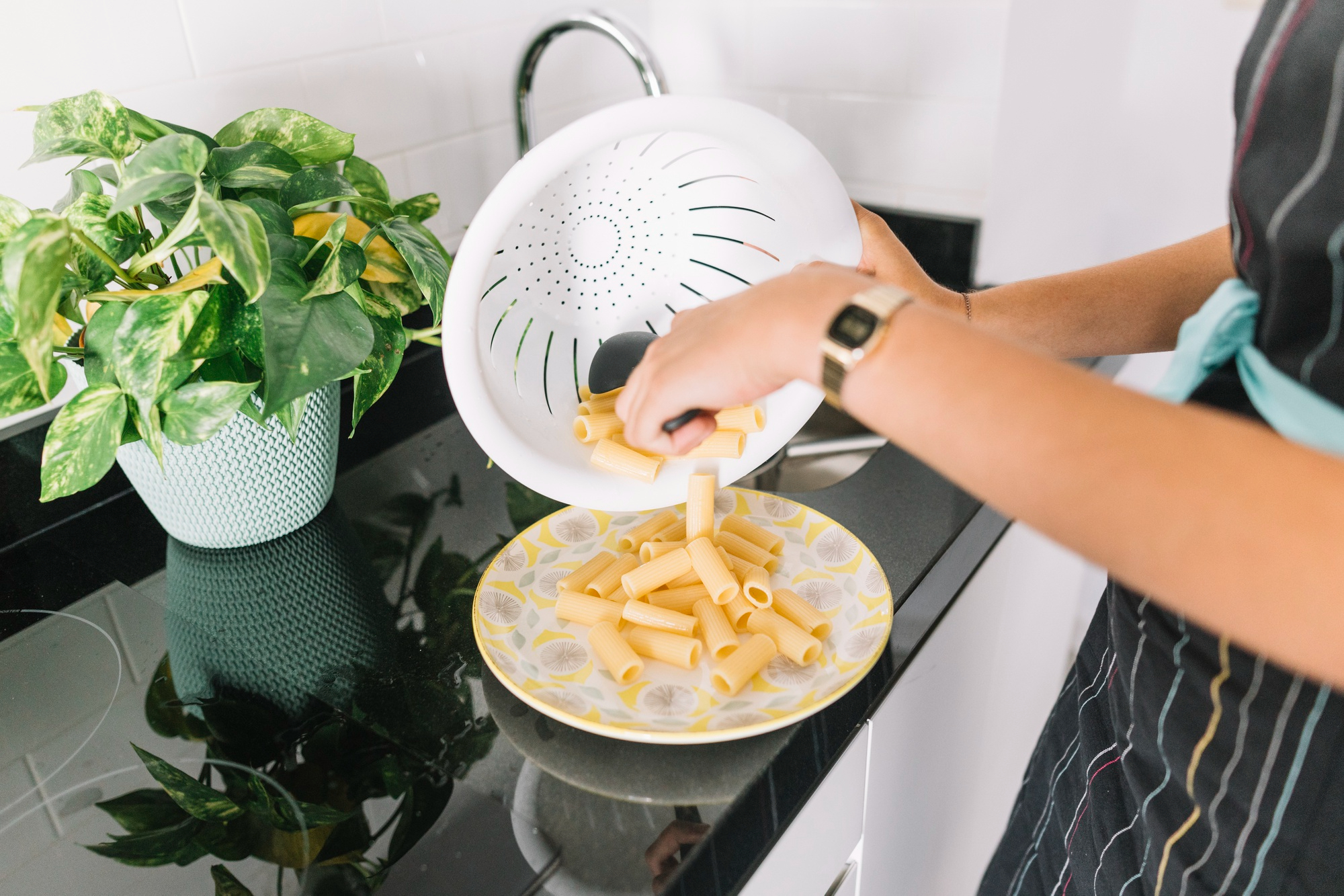 A woman pouring cooked pasta into a plate | Source: Freepik