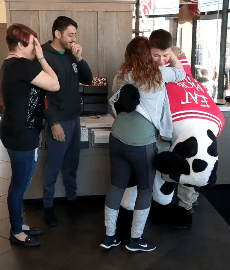 Brandy Rodriguez hugging Antonio Rodriguez who is in the Chick-fil-A cow costume as their family looks on. | Source: facebook.com/cfaskibo
