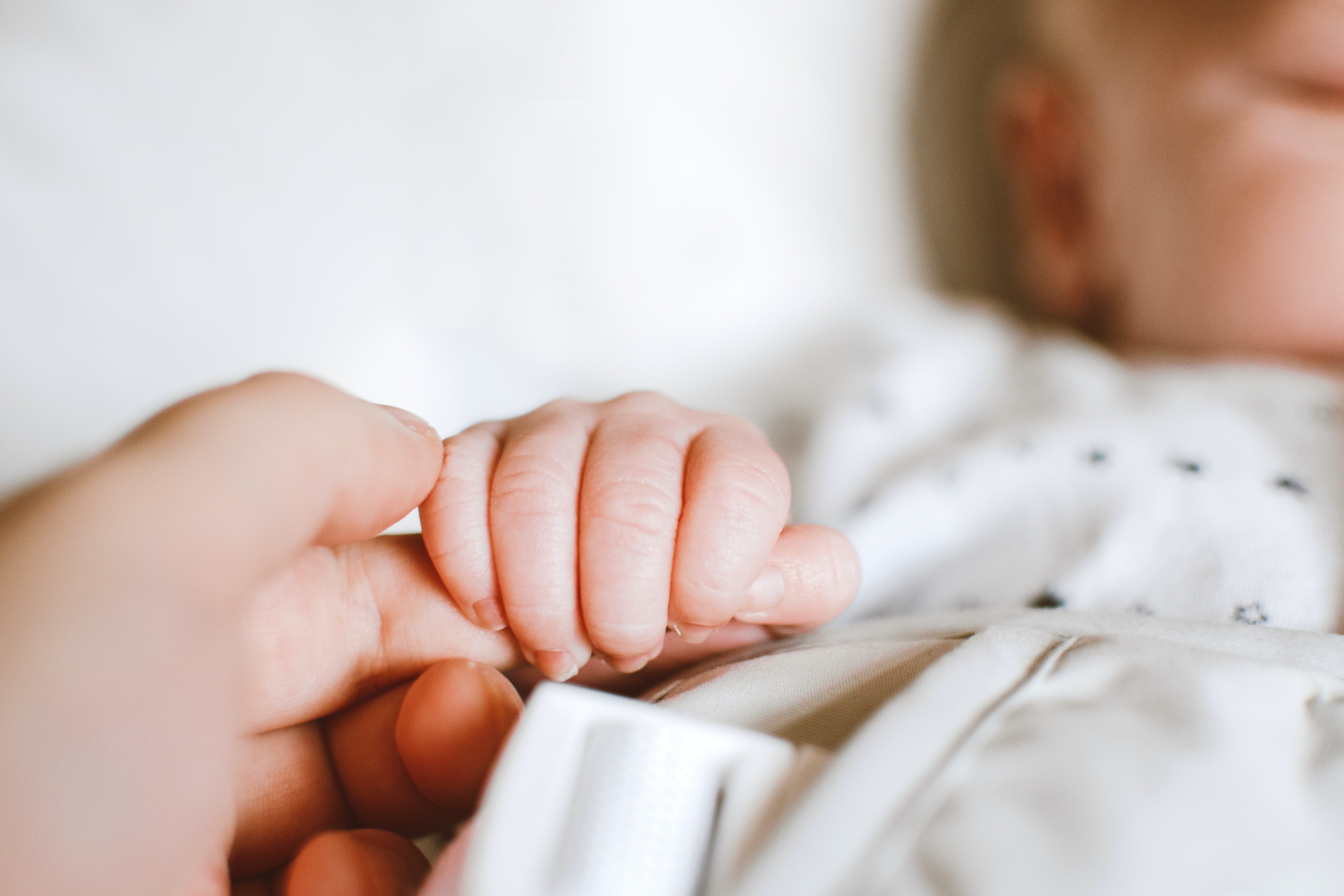 A baby's hand clutching a woman's finger | Source: Pexels