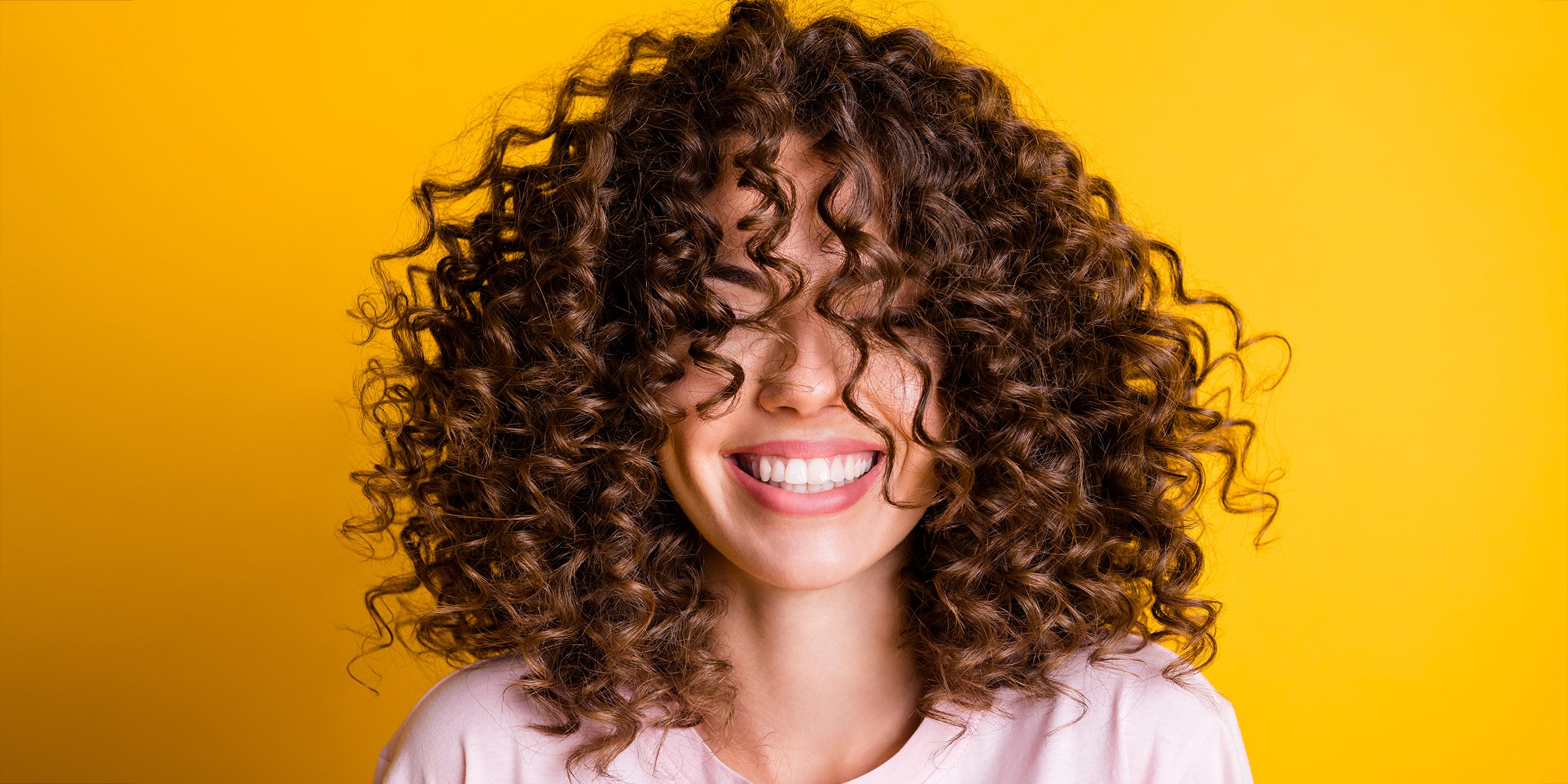 A Woman with Type 3A Hair Smiling with Her Eyes Closed | Source: Shutterstock