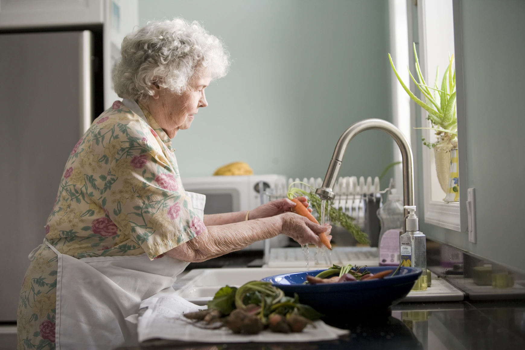 An older lady is pictured washing a carrot. | Source: Unsplash
