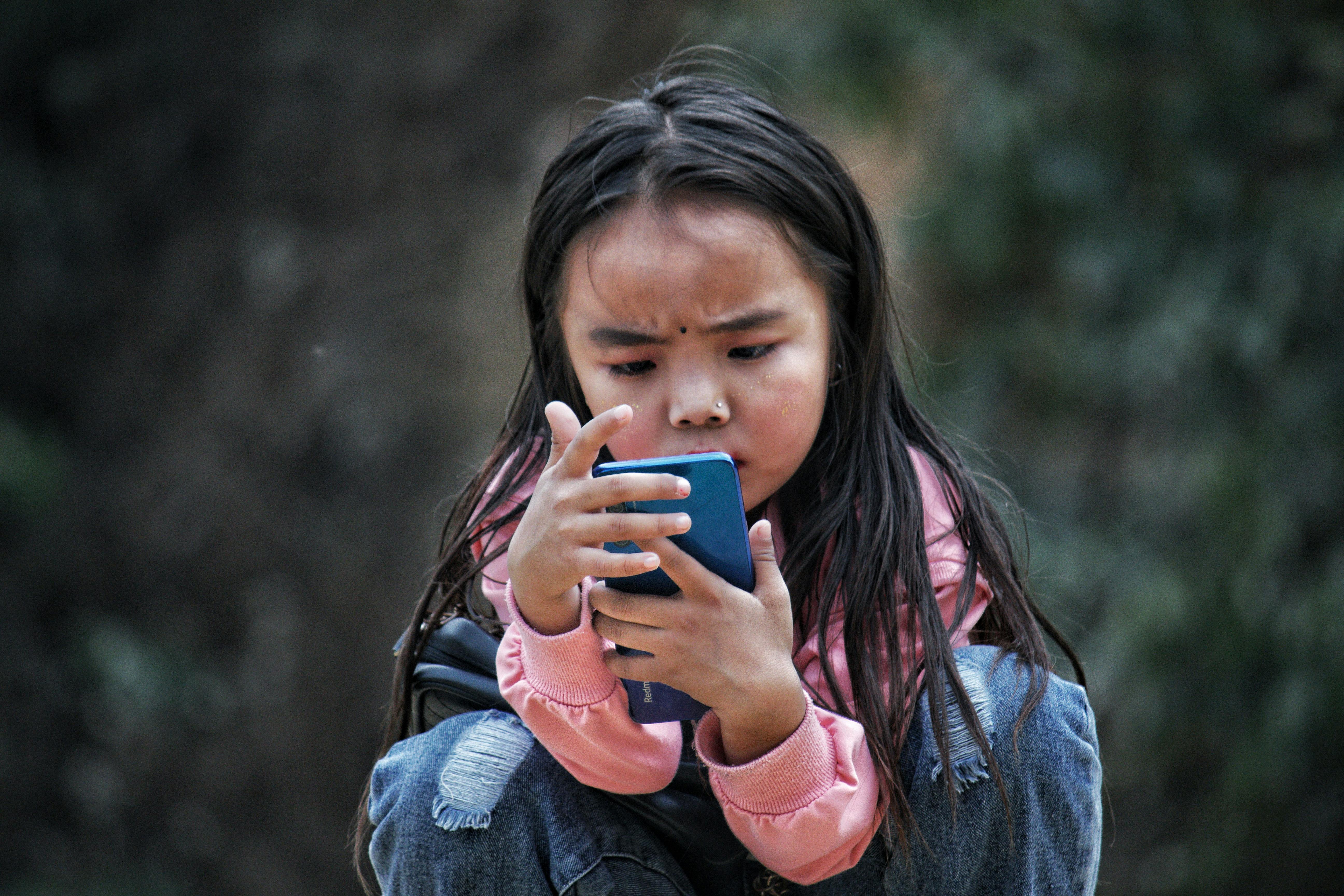 A little girl fiddling with a cellphone | Source: Pexels