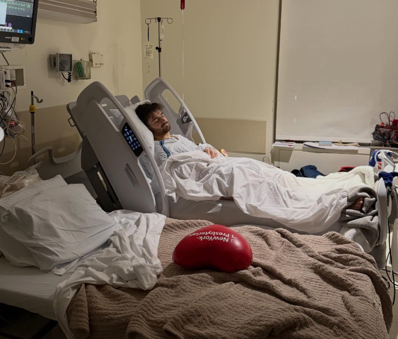 Daniel Neeson rests in a hospital bed surrounded by medical monitors and equipment, covered in white sheets. | Source: Instagram/bgdans91
